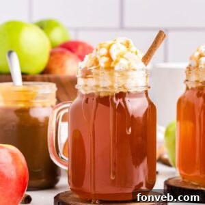 Cozy Caramel Apple Brew 18 A mason jar filled with Crock Pot Caramel Apple Cider, topped with whipped cream and a drizzle of golden caramel syrup.
