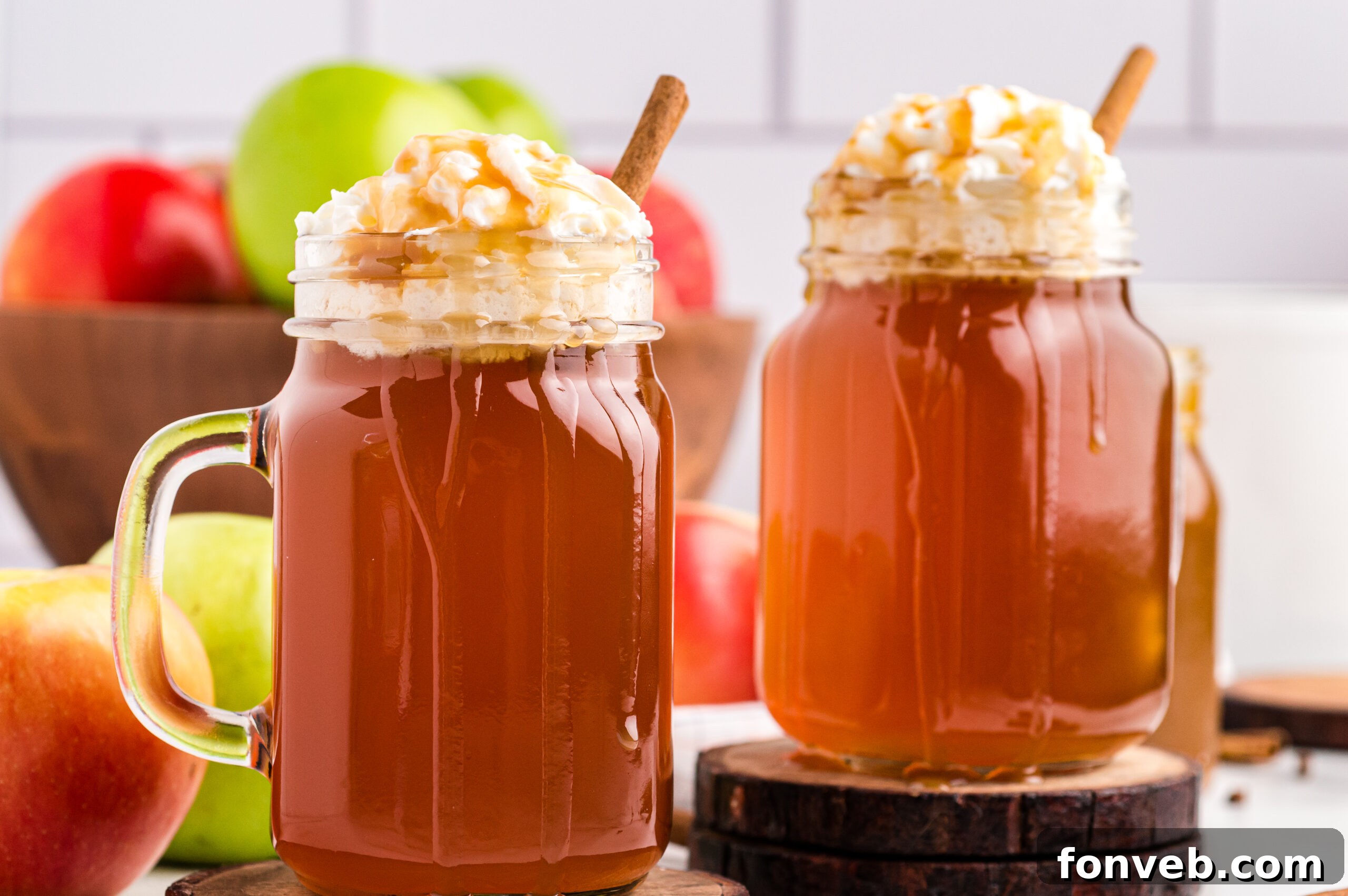 Cozy Caramel Apple Brew 3 Two mason jars of Crock Pot Caramel Apple Cider with whipped cream and caramel drizzle, ready to be enjoyed.