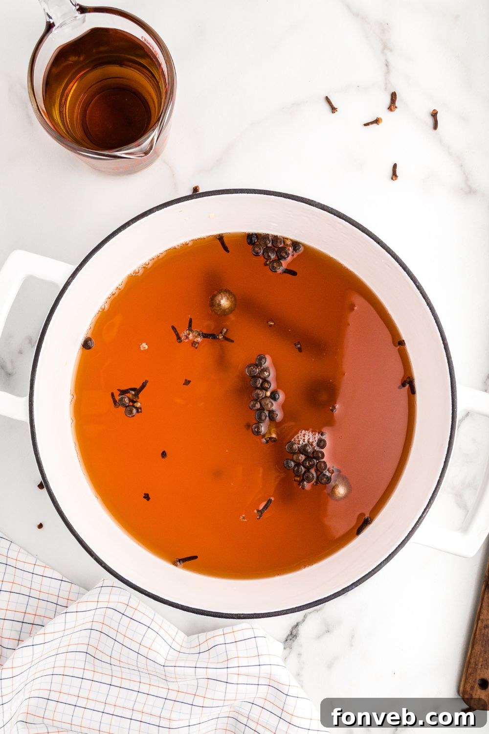 Cozy Caramel Apple Brew 6 A pot of caramel apple cider mixture simmering gently on a stovetop, with whole spices visible.