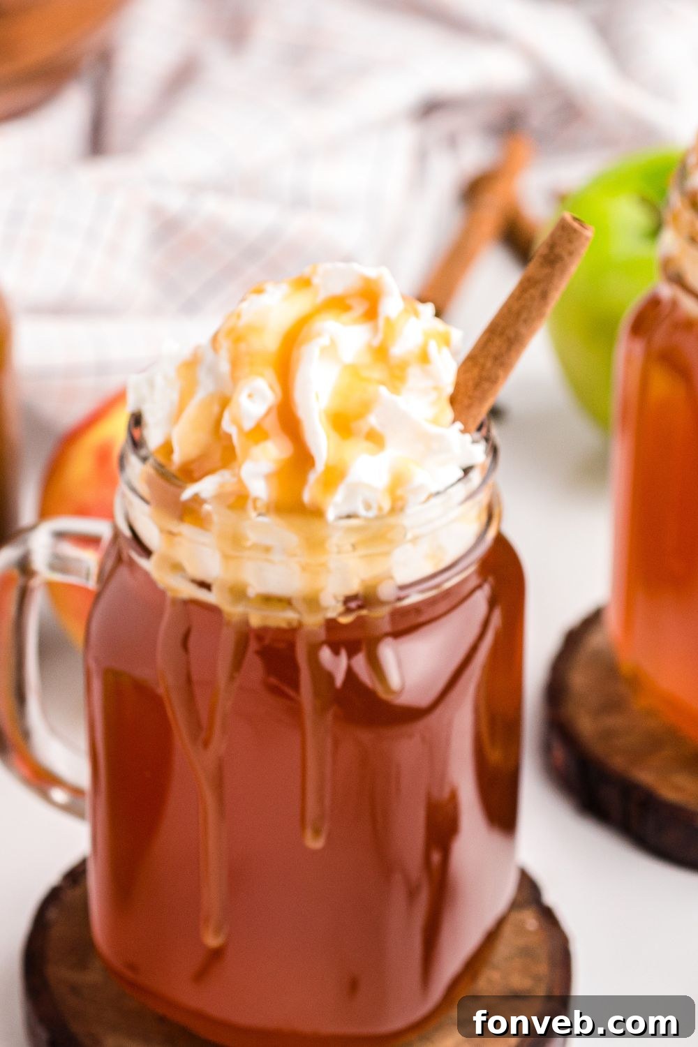 Cozy Caramel Apple Brew 8 A close-up of a glass of caramel apple cider, beautifully topped with whipped cream and a luscious caramel drizzle.