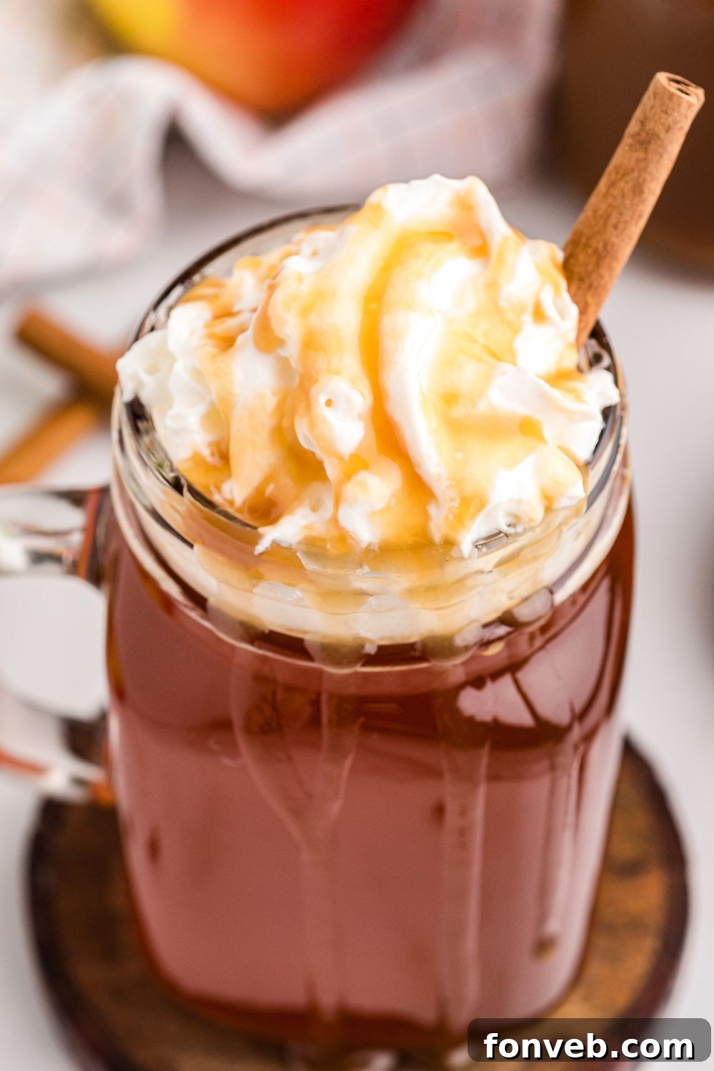 Cozy Caramel Apple Brew 9 A single glass of warm apple cider, garnished with a cinnamon stick, sitting on a rustic wooden table.