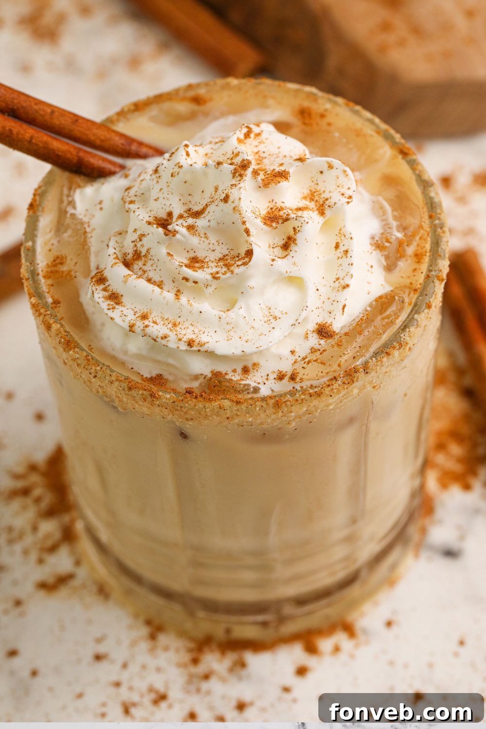 A pumpkin pie white russian cocktail in a glass, surrounded by pumpkin spice seasoning on a table, creating a festive autumn scene.