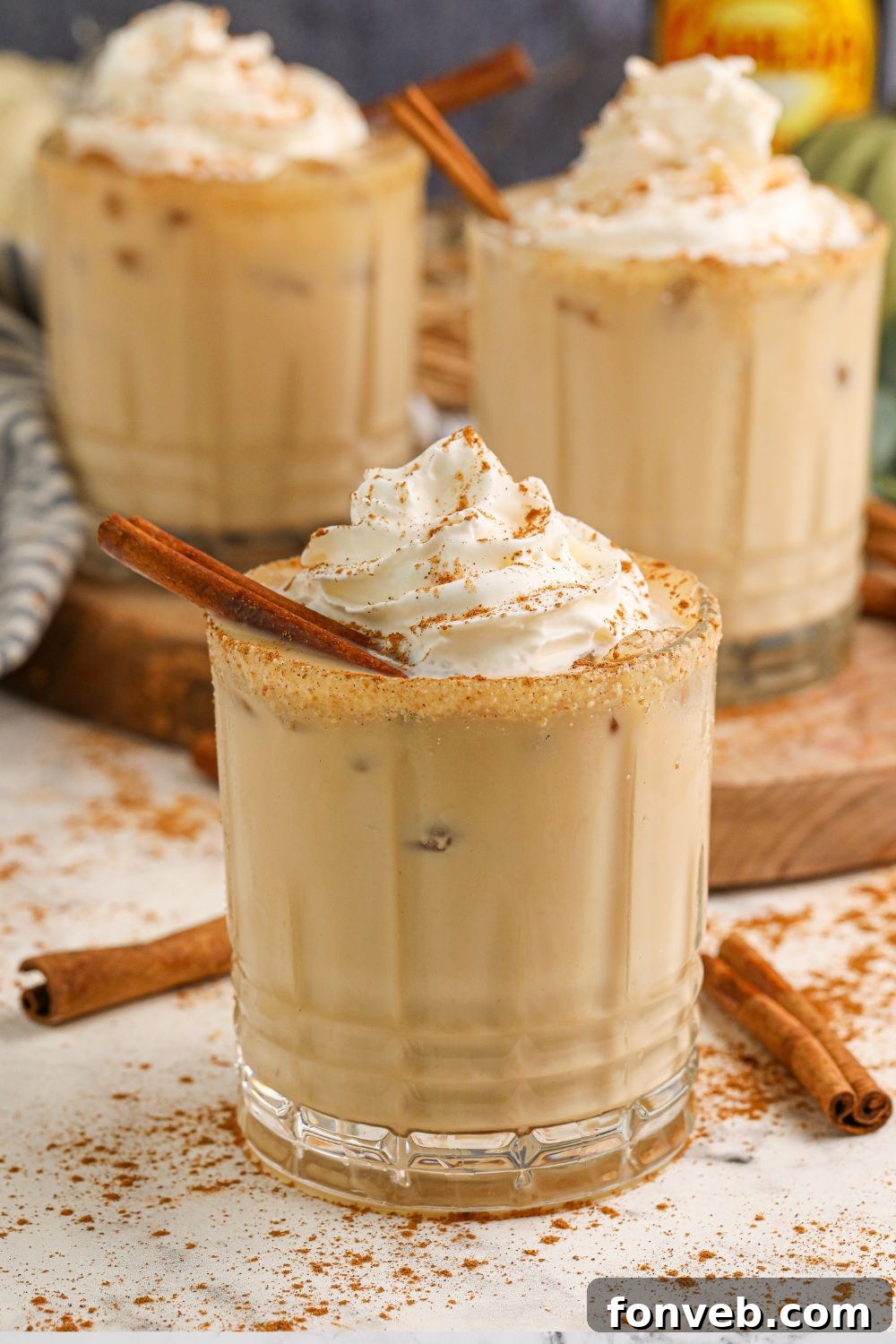 Multiple pumpkin spice white russian cocktails in glasses, elegantly placed on a table, creating a festive and cozy ambiance.