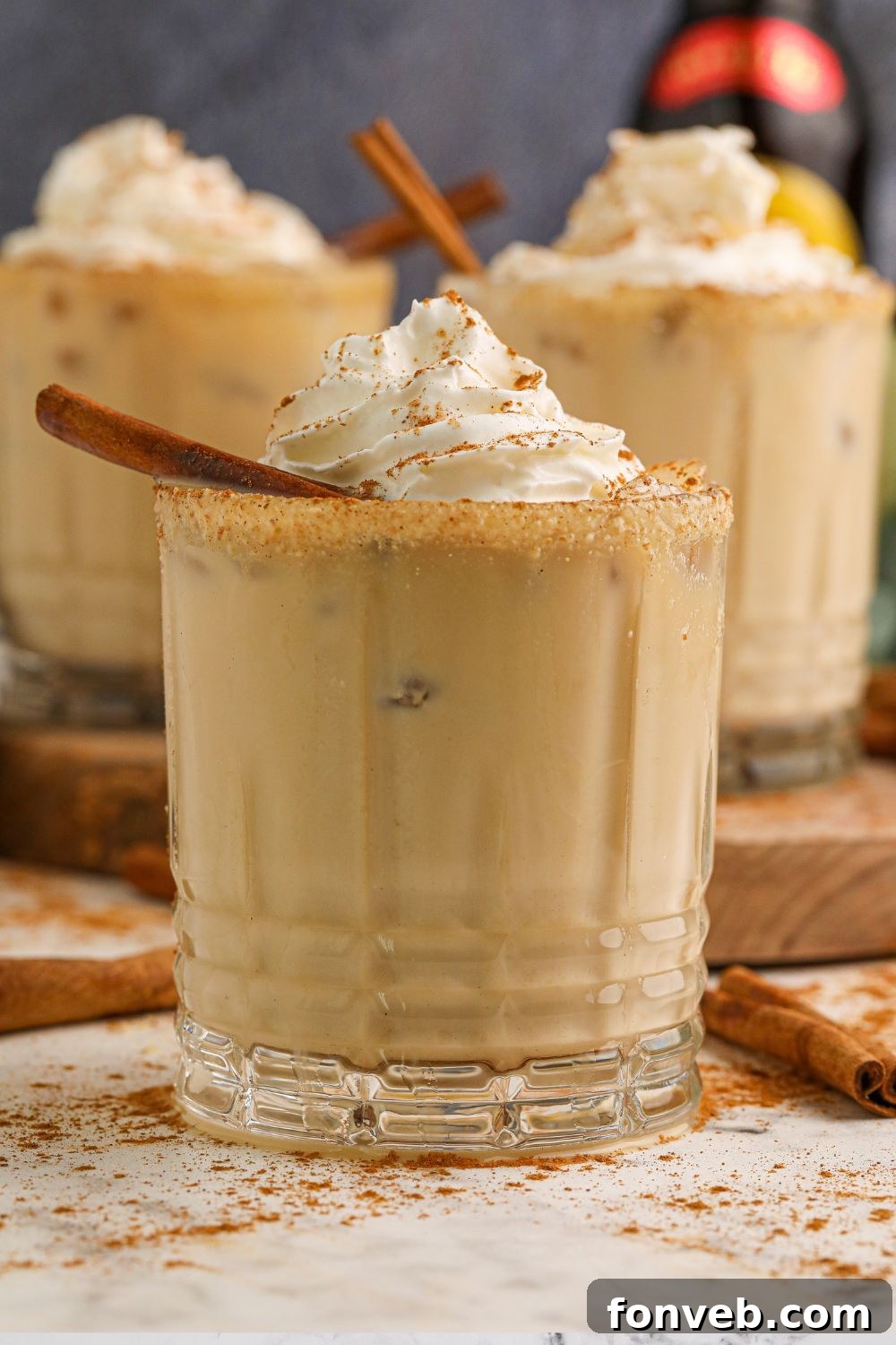 A trio of pumpkin spice white russian cocktails, arranged on a rustic table, inviting a sense of warmth and seasonal cheer.