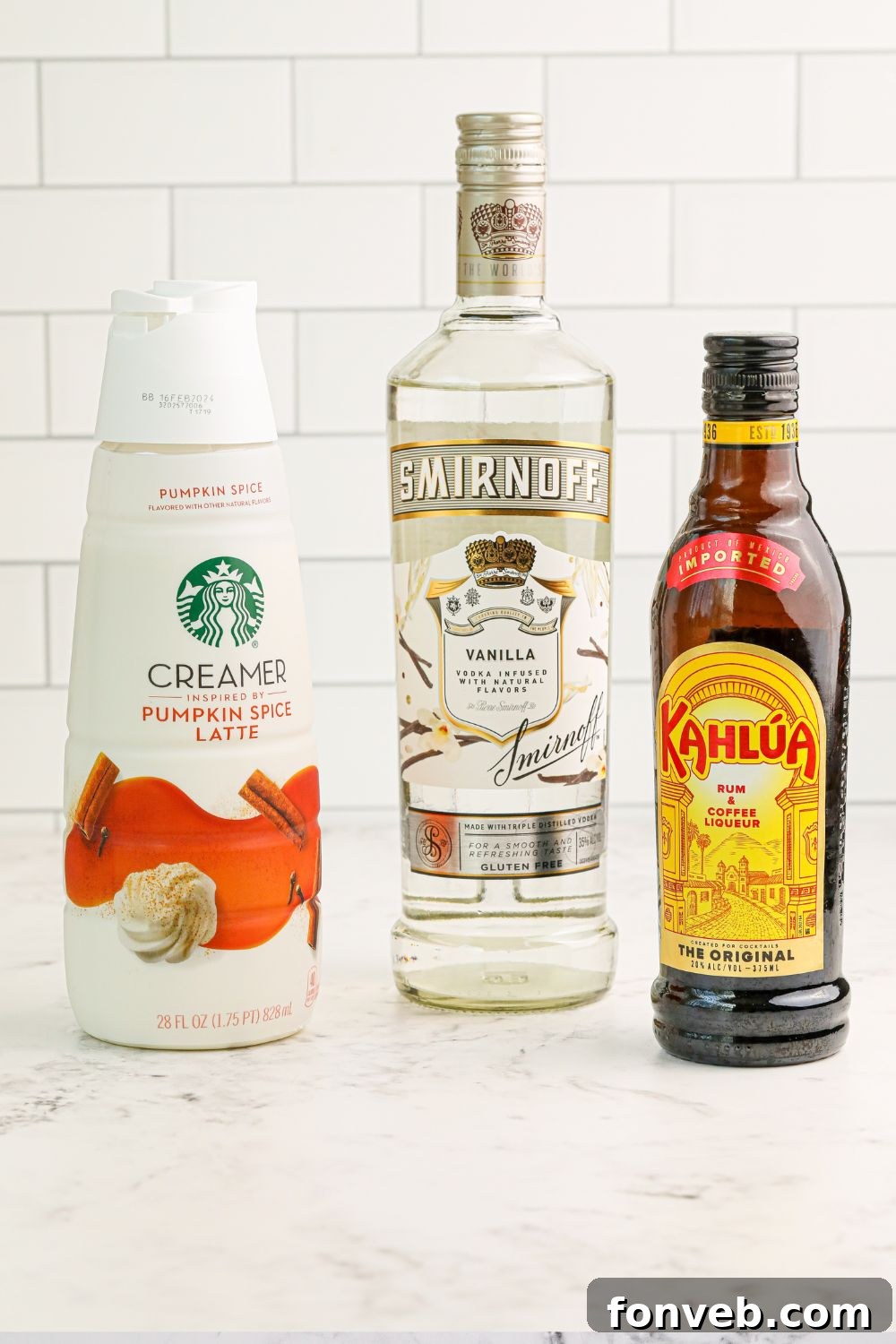 Various ingredients for a Pumpkin White Russian cocktail neatly arranged on a pristine white table, ready for mixing.