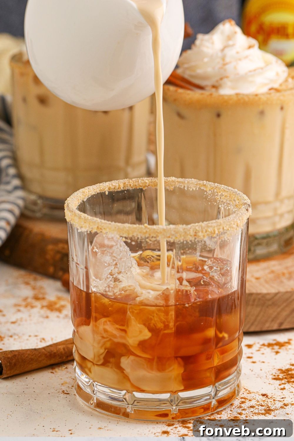 Pouring rich pumpkin spice creamer into a cocktail glass, illustrating the creamy texture and color.