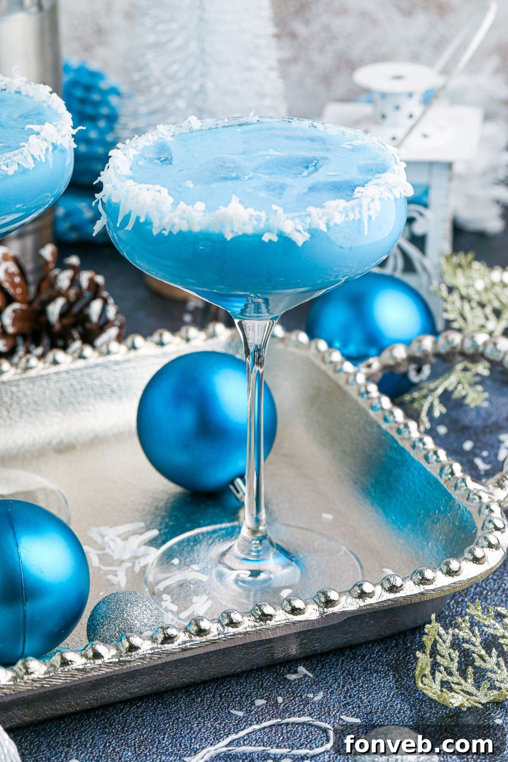 Blue Christmas Cocktail presented on a table, elegantly surrounded by coordinating blue Christmas ornaments, setting a festive scene