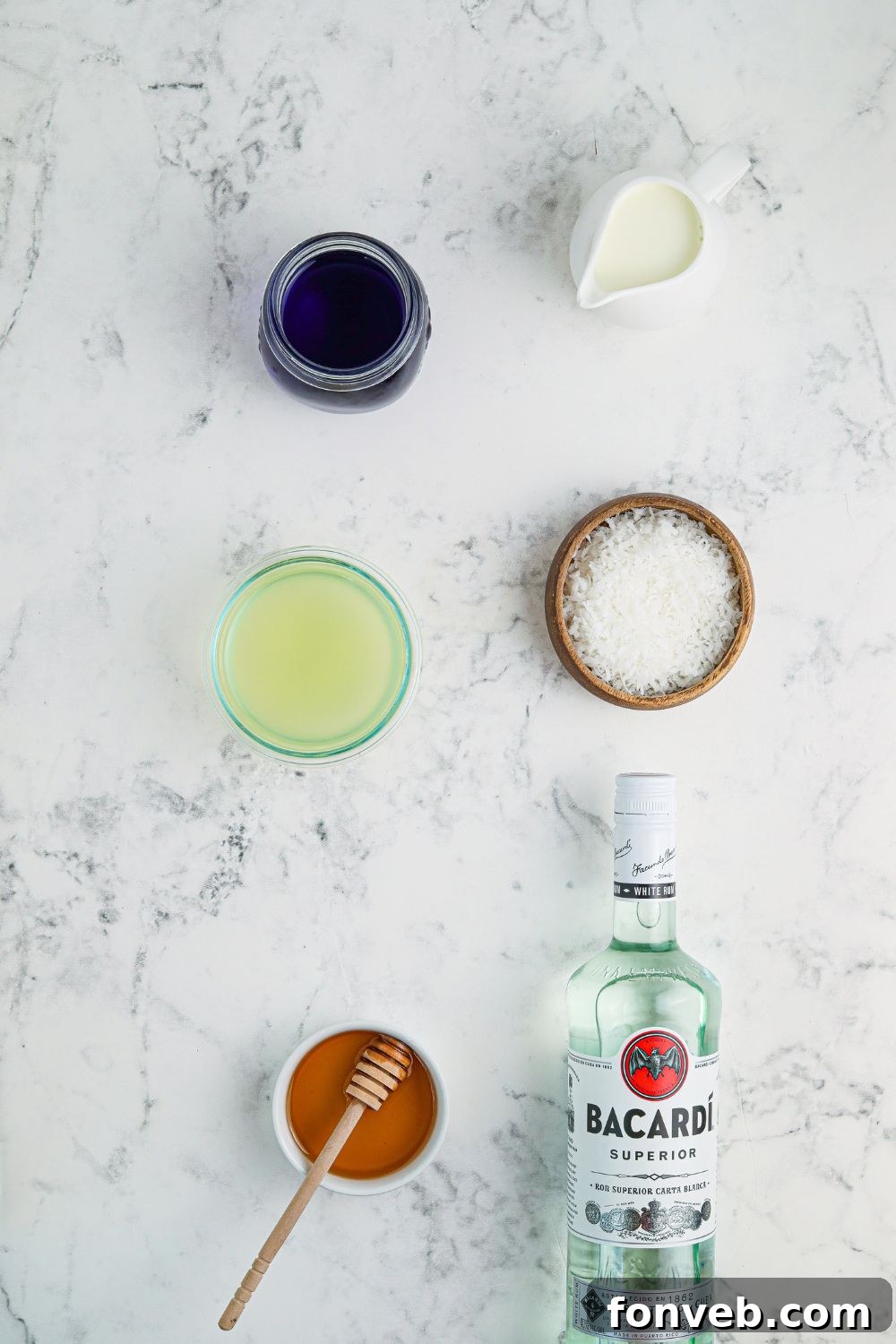 Bowls of fresh pineapple juice, Blue Curacao, coconut milk, and rum, ready for cocktail mixing