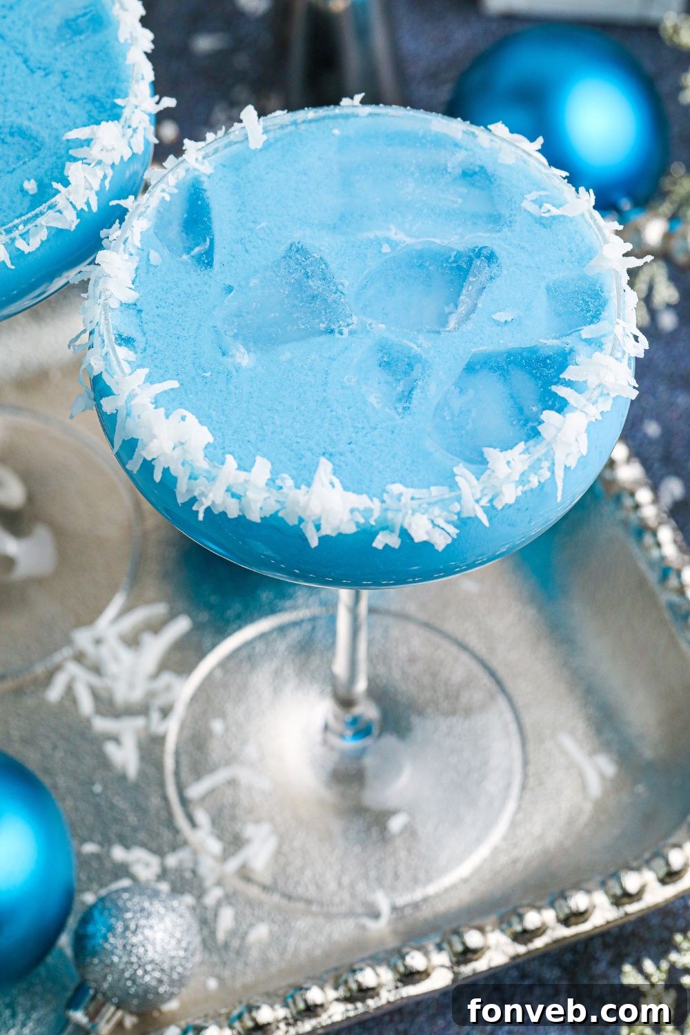 A single Blue Christmas Cocktail elegantly presented on a silver platter, surrounded by ambient lighting