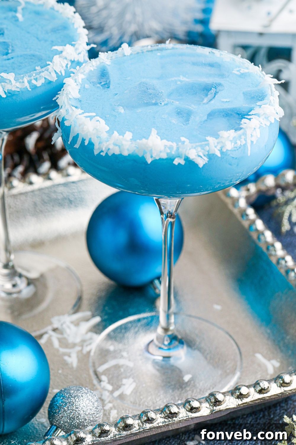 A mesmerizing blue cocktail presentation, adorned with festive Christmas ornaments for a touch of holiday magic