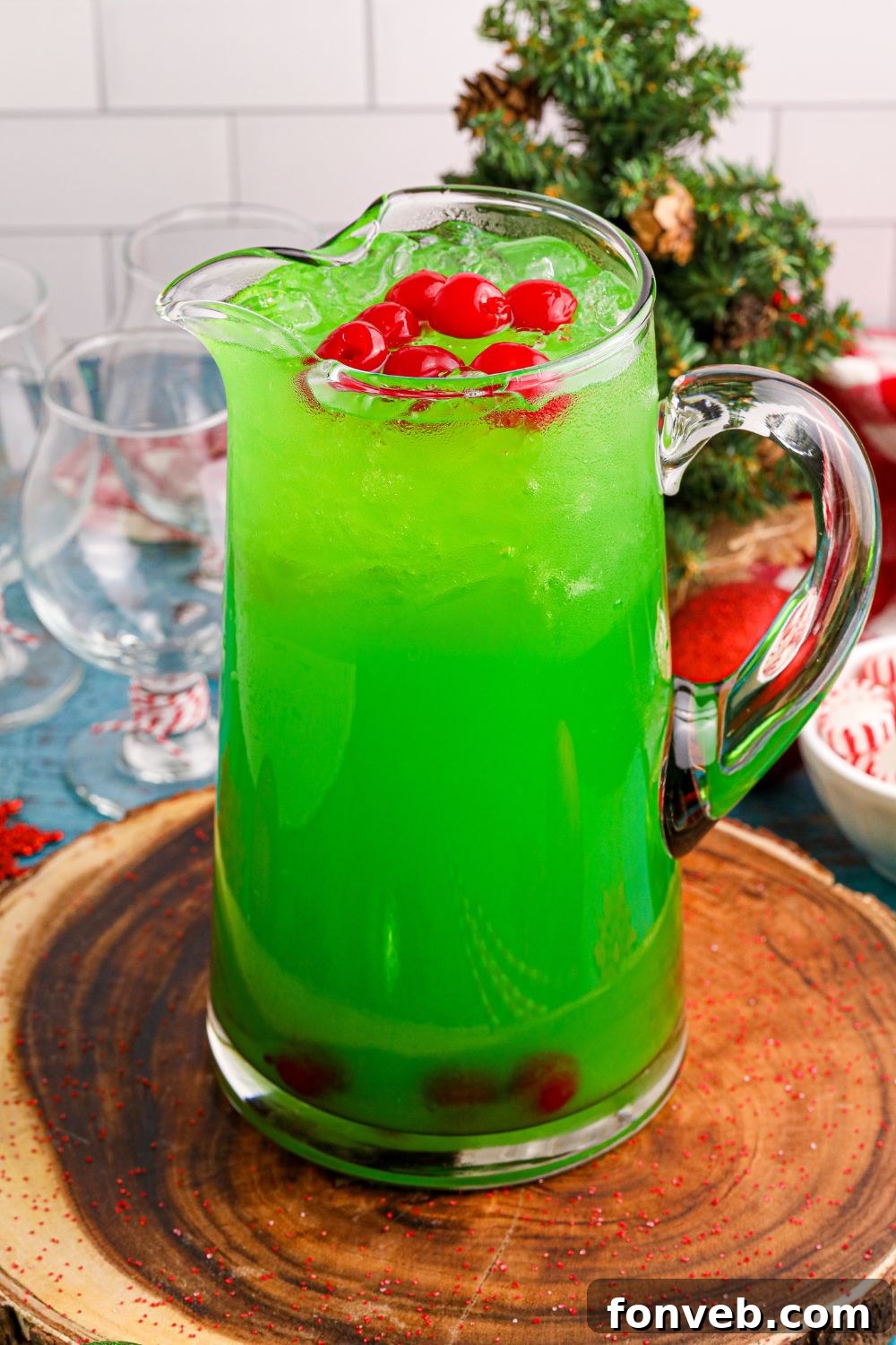 green grinch punch in a pitcher sitting on table with Christmas decor around it