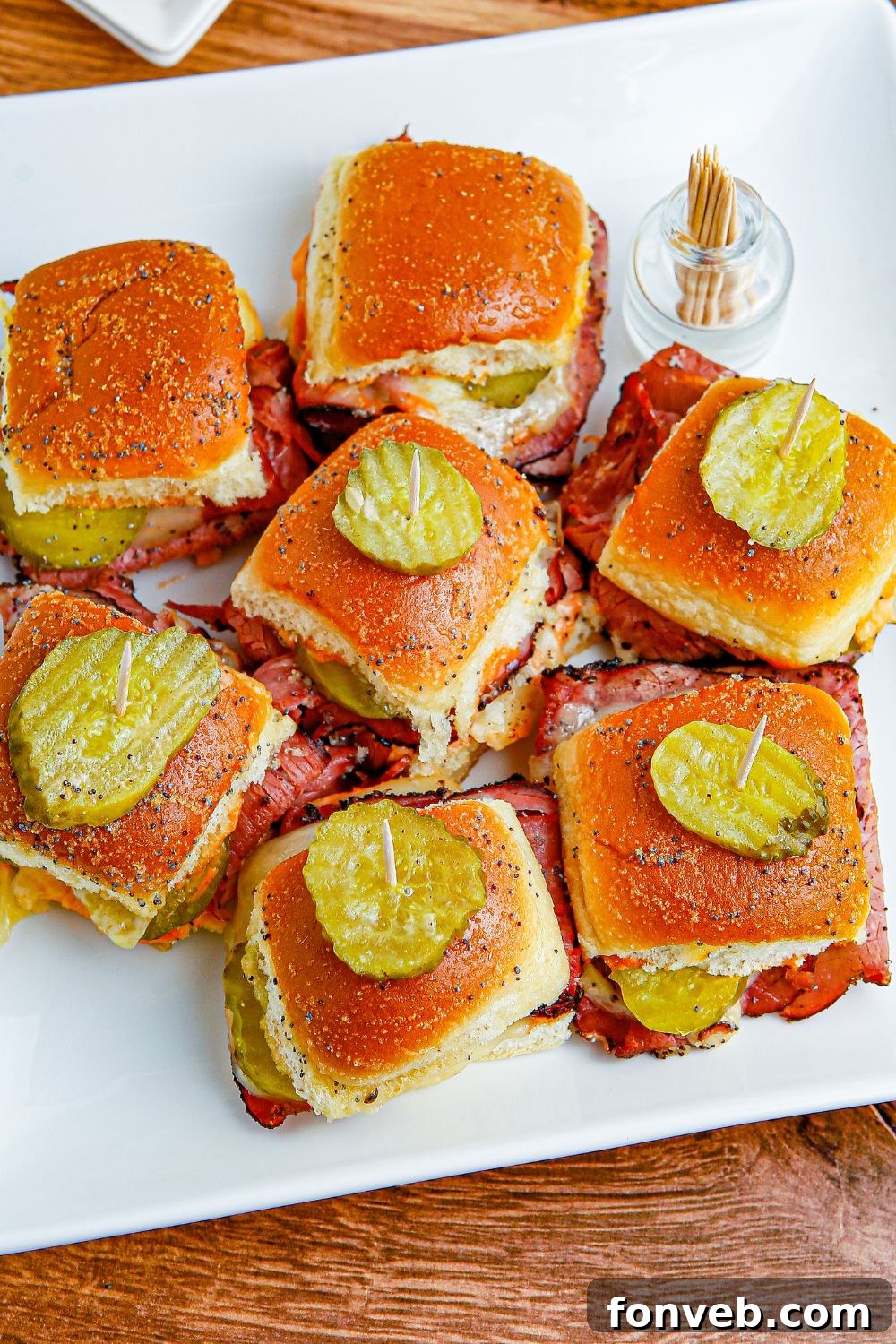 Pastrami Sliders on a table with pickles on top 