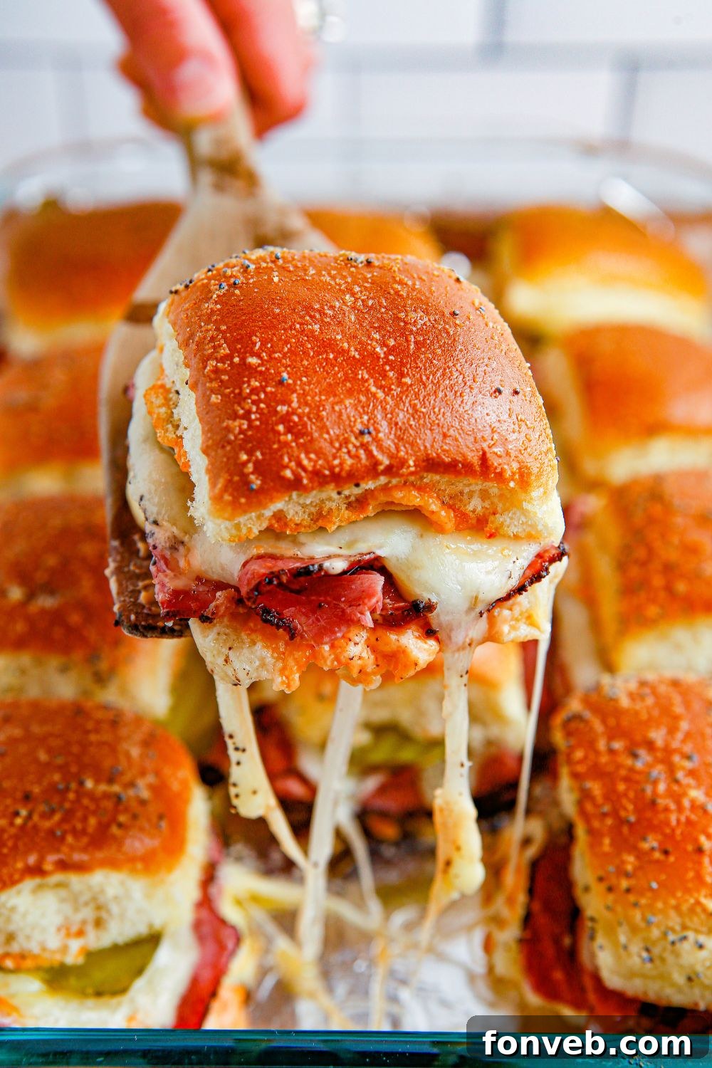 Pastrami Slider being lifted out of pan with cheese stringing out of it 