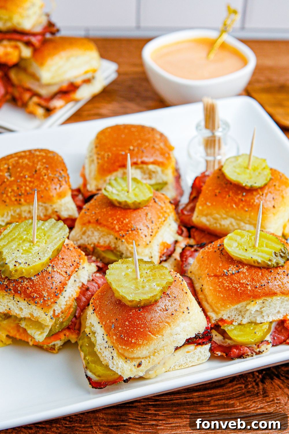 tray with a handful of sandwiches on and dip in a white bowl behind it 