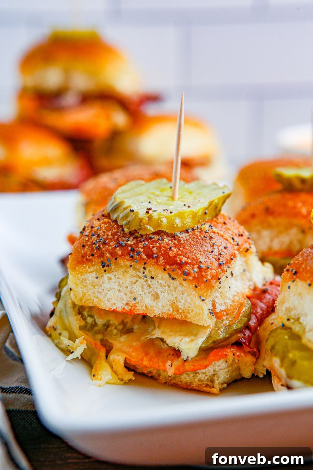 seasoned bun laded with cheese and pastrami and topped with a pickle and toothpick