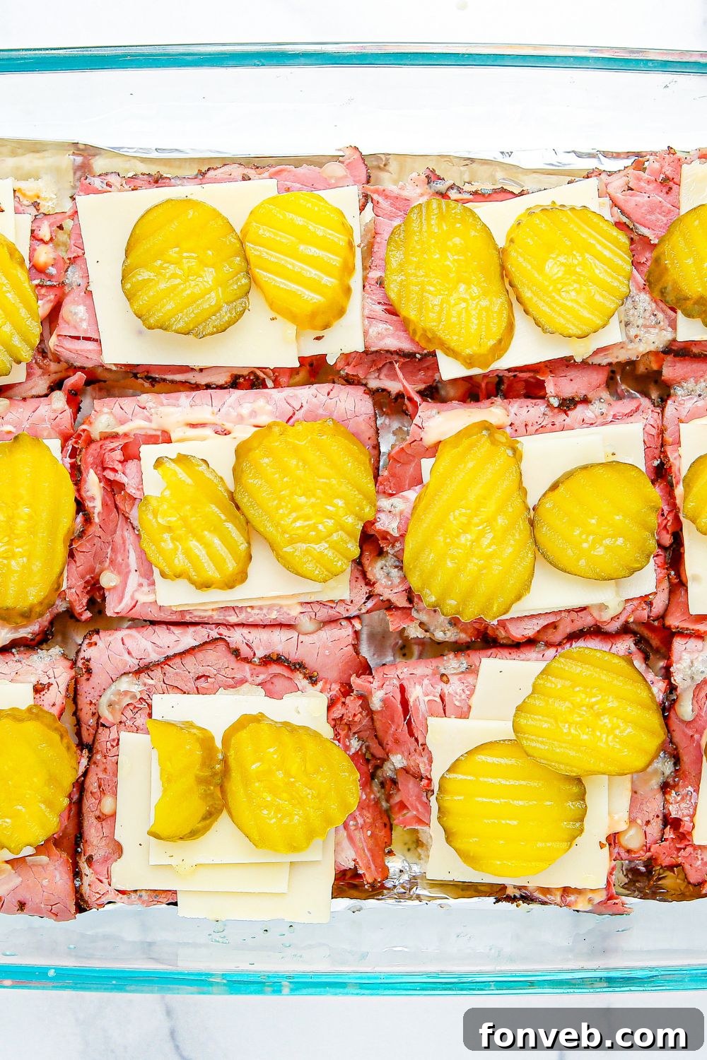 sliders with meat, cheese and pickles on top