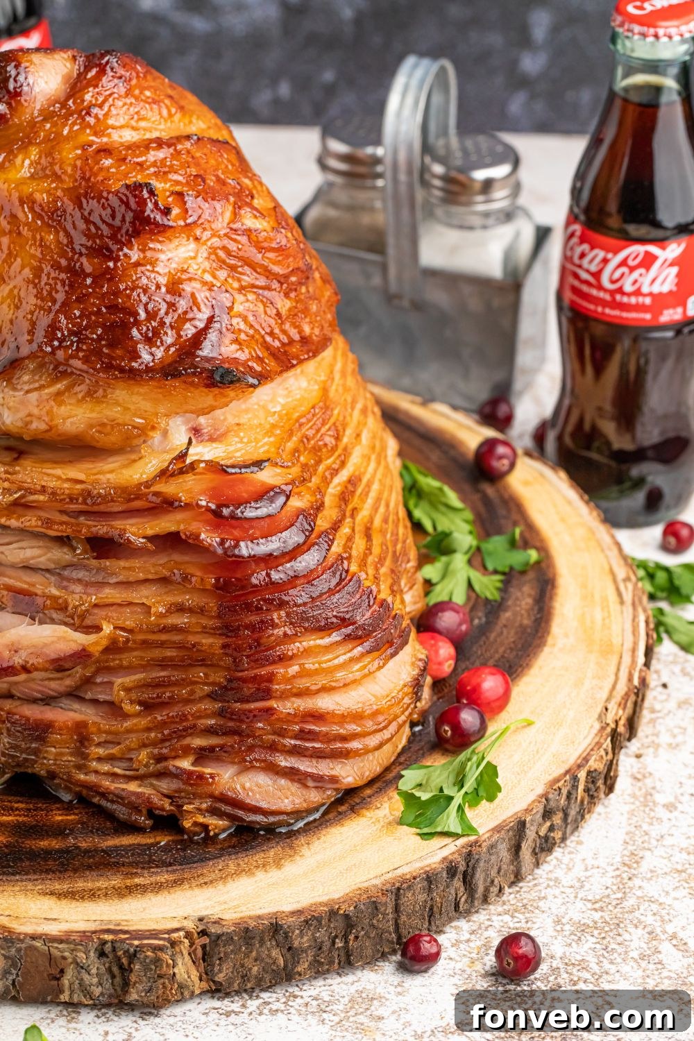spiral ham on wooden platter with salt and pepper behind it and coke