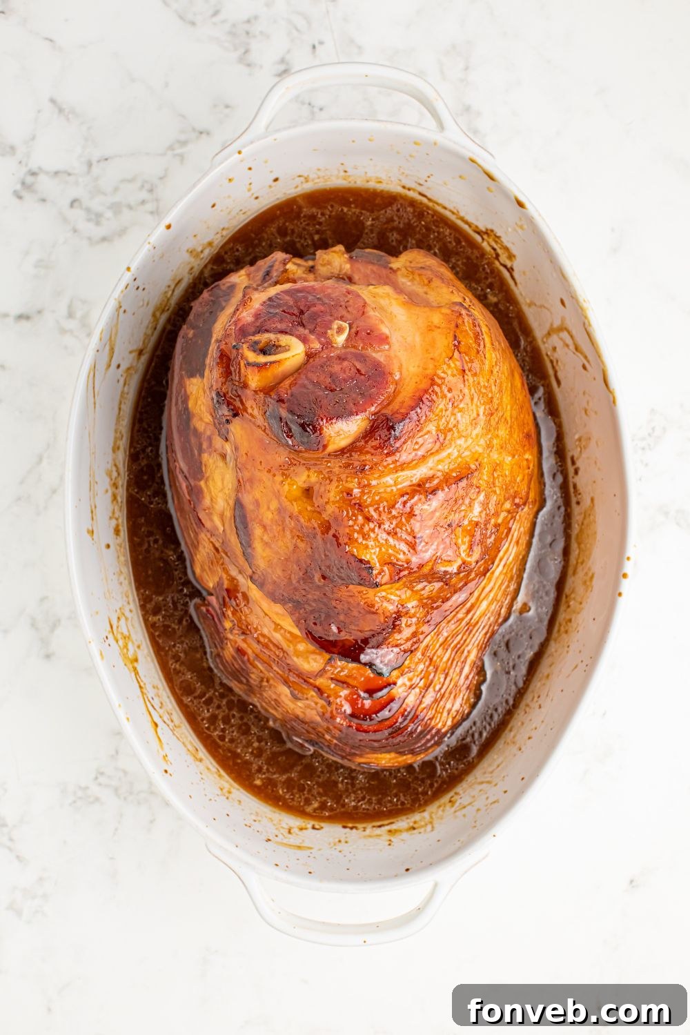 cooked ham with glaze in bottom of pan