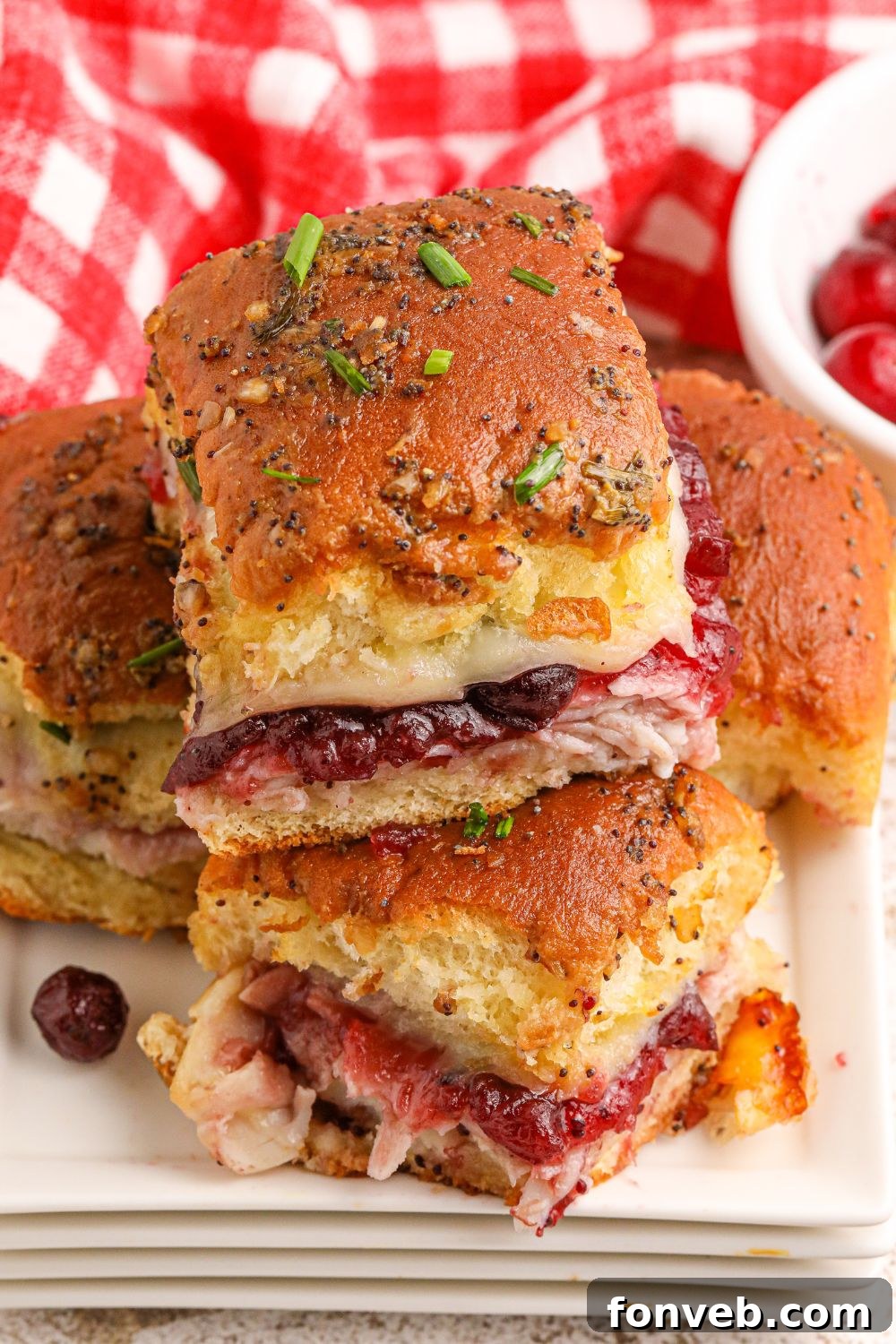 Up close shot of Thanksgiving Sliders stacked on a plate, showing the layers of turkey, cranberry, and cheese