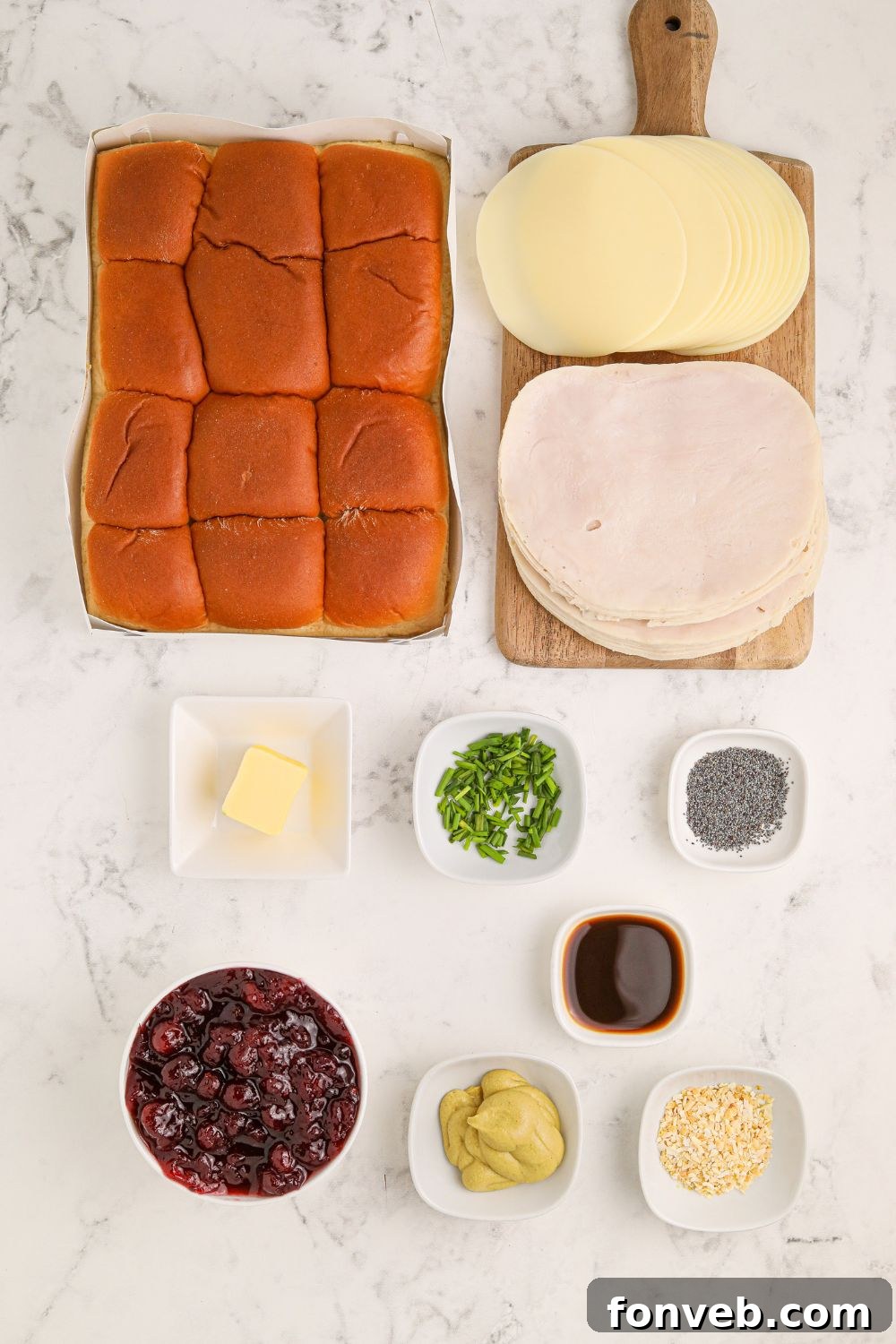 Ingredients for turkey cranberry sliders laid out on a table, including rolls, turkey, cranberry sauce, and topping components