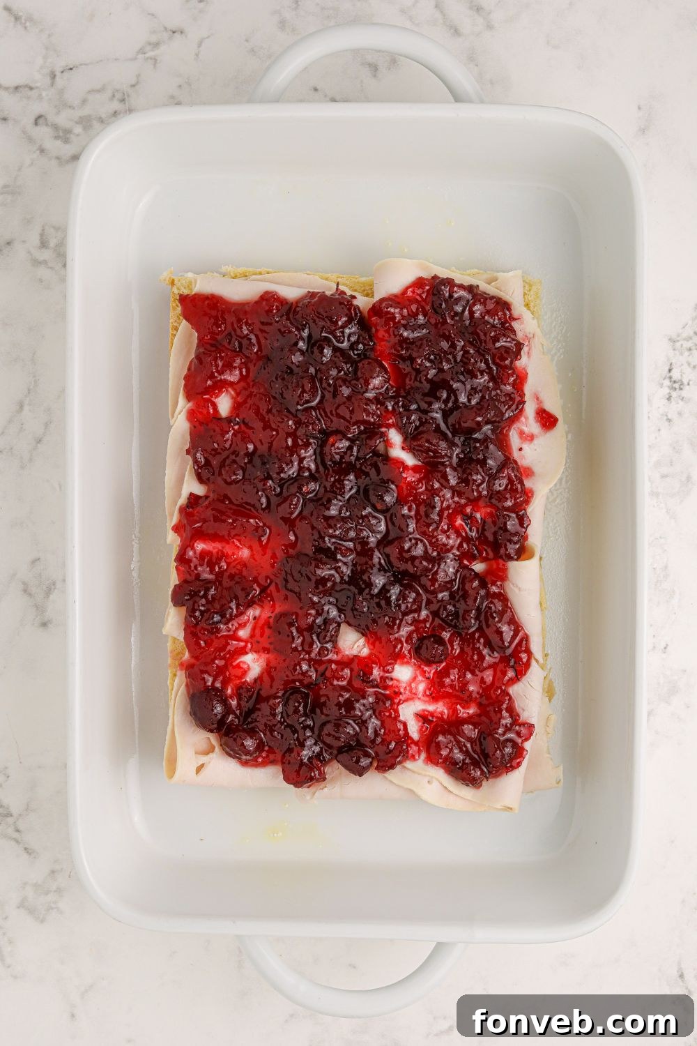 cranberry sauce spread evenly on the bottom layer of slider rolls