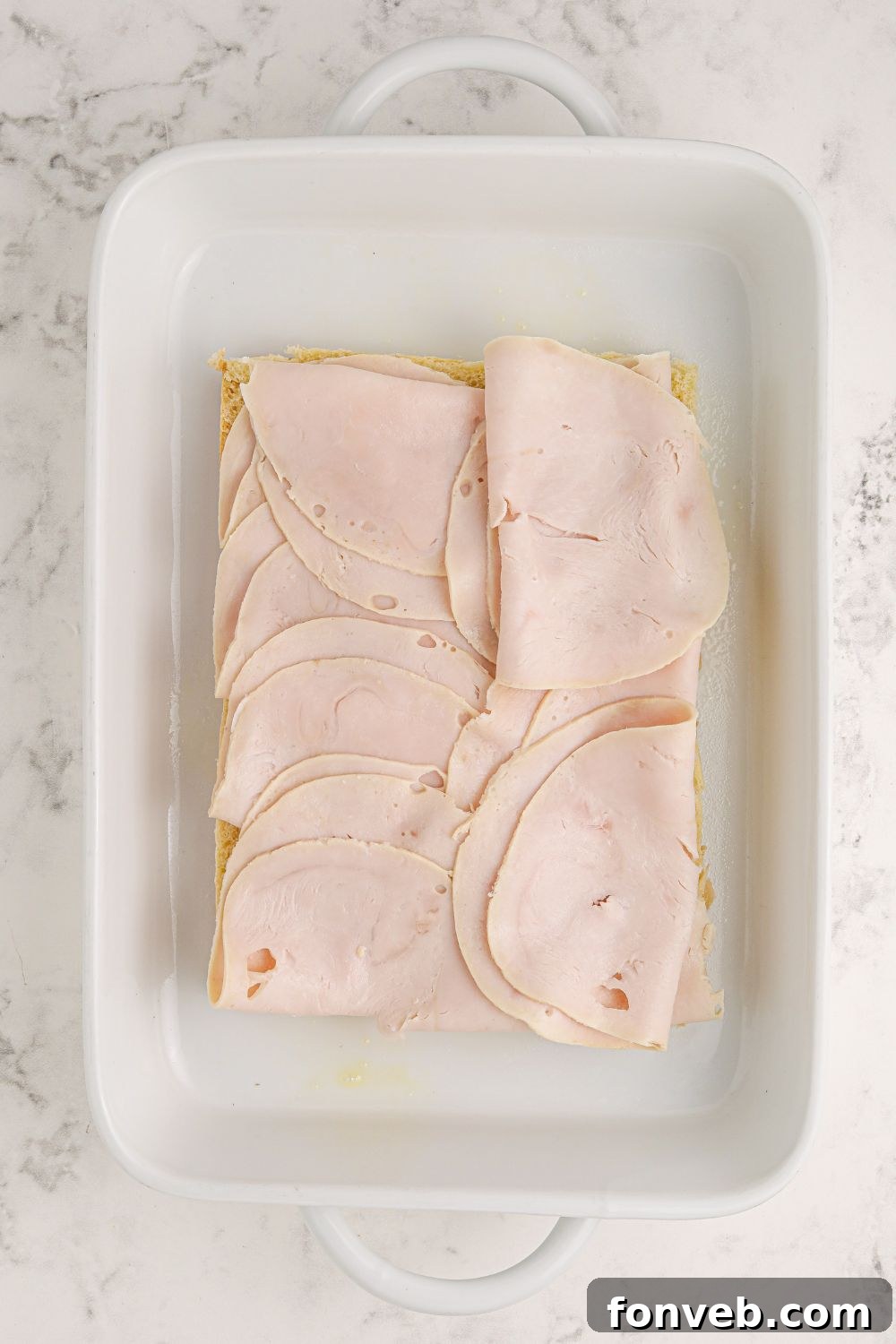 sliced turkey meat layered on top of slider buns