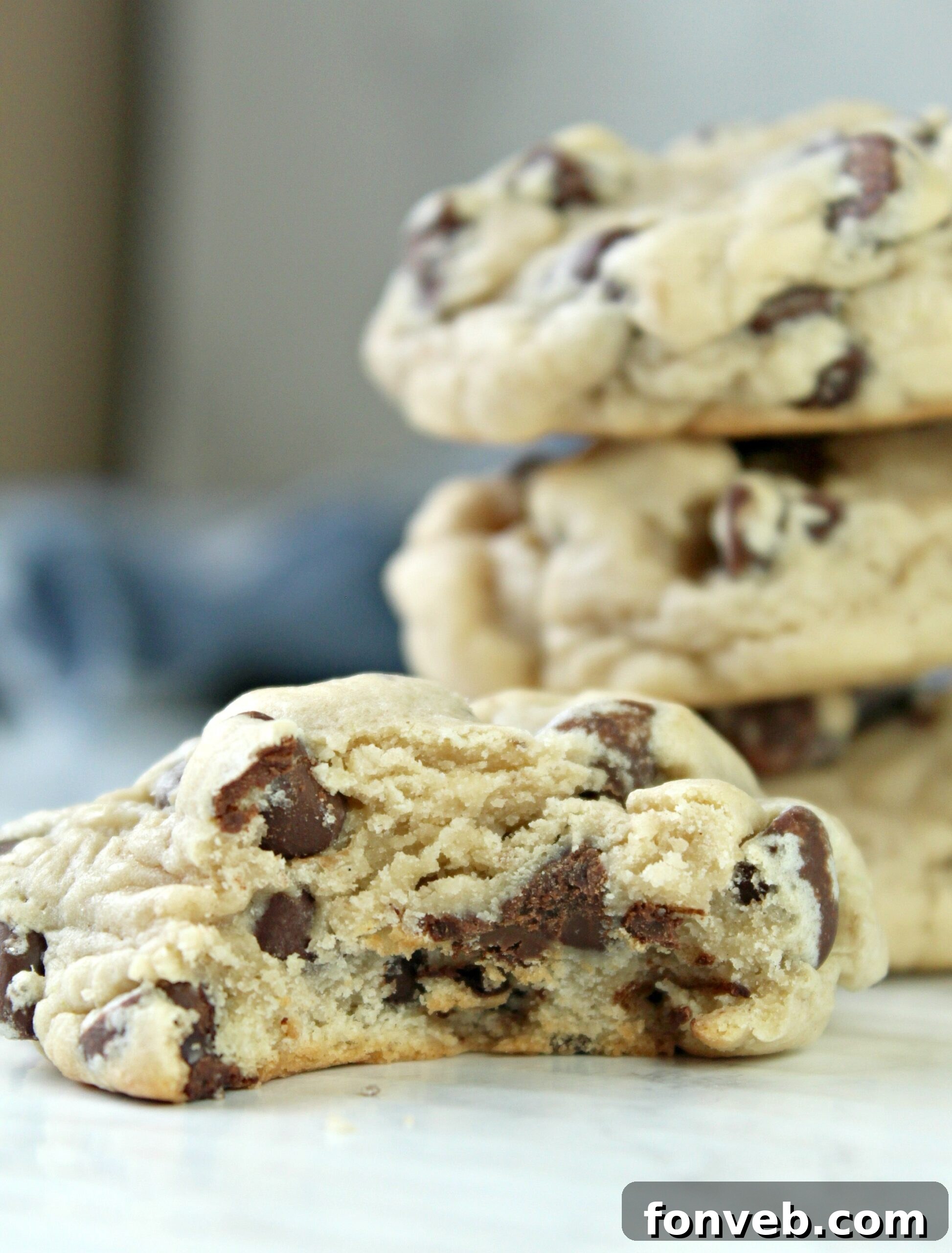 A delectable, soft-baked cookie rests on a wooden table, with a bite playfully taken out, revealing its rich texture and inviting warmth.
