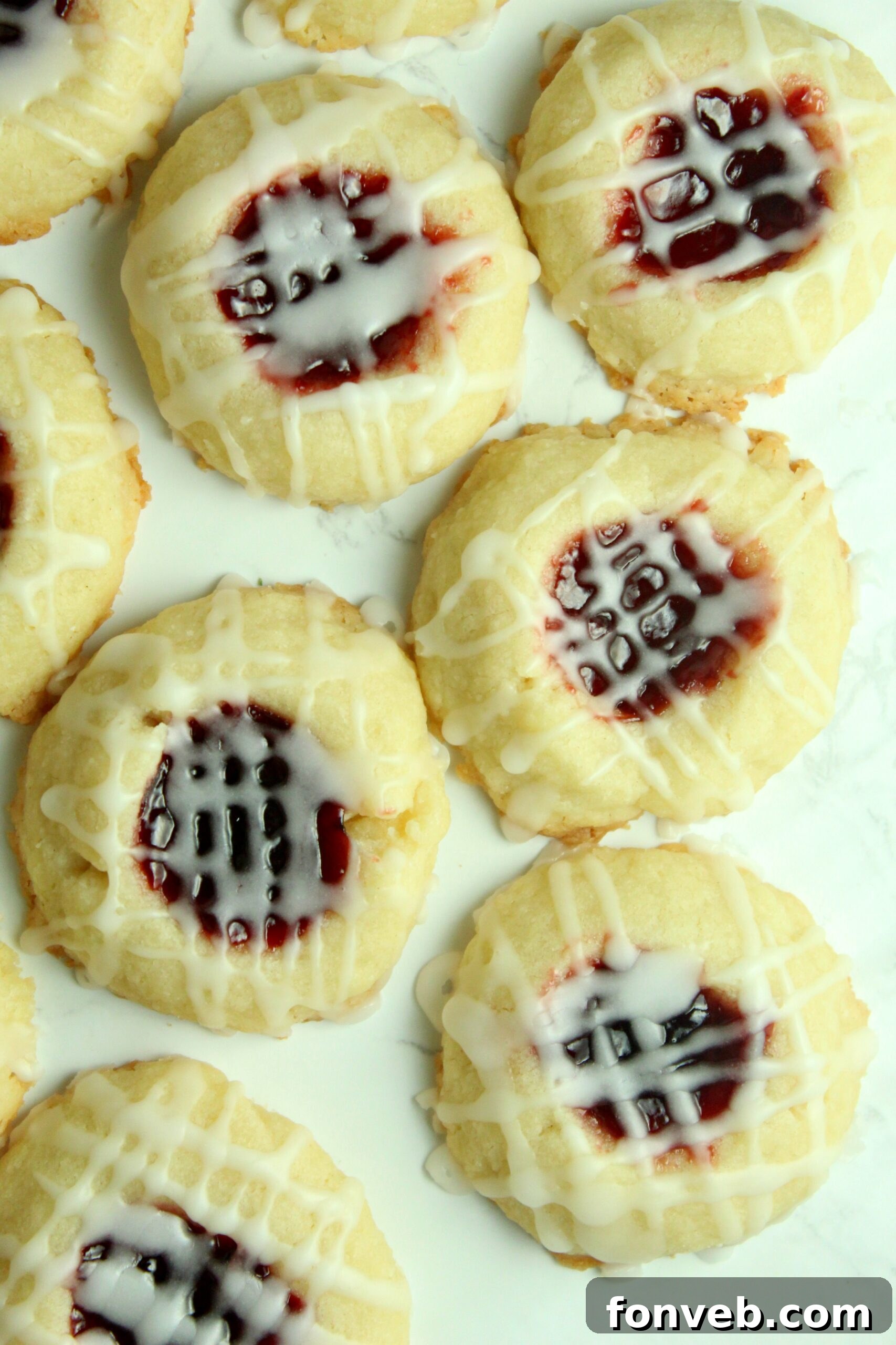 A delicious array of thumbprint cookies, each with a fruit jam center, arranged enticingly on a rustic baking table, highlighting their delicate form.
