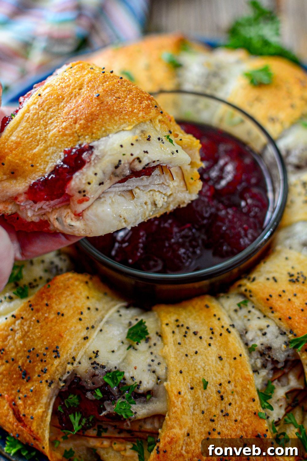 A slice of crescent turkey ring held in hand, showing the cheesy filling