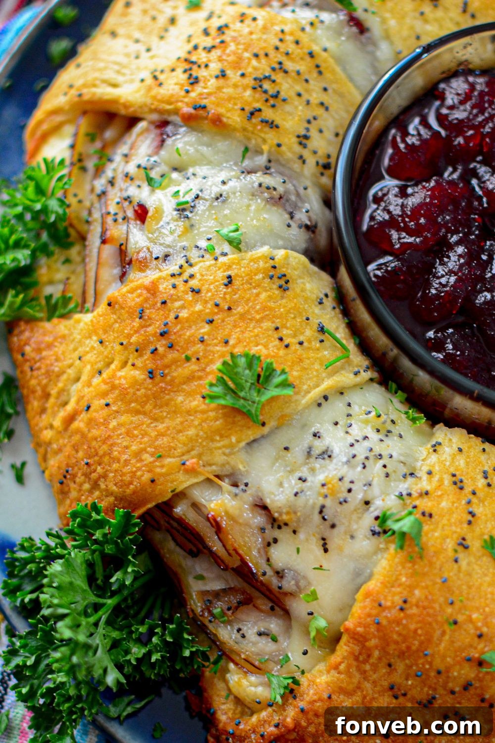 A golden-brown cheesy crescent roll wreath on a baking sheet, fresh out of the oven