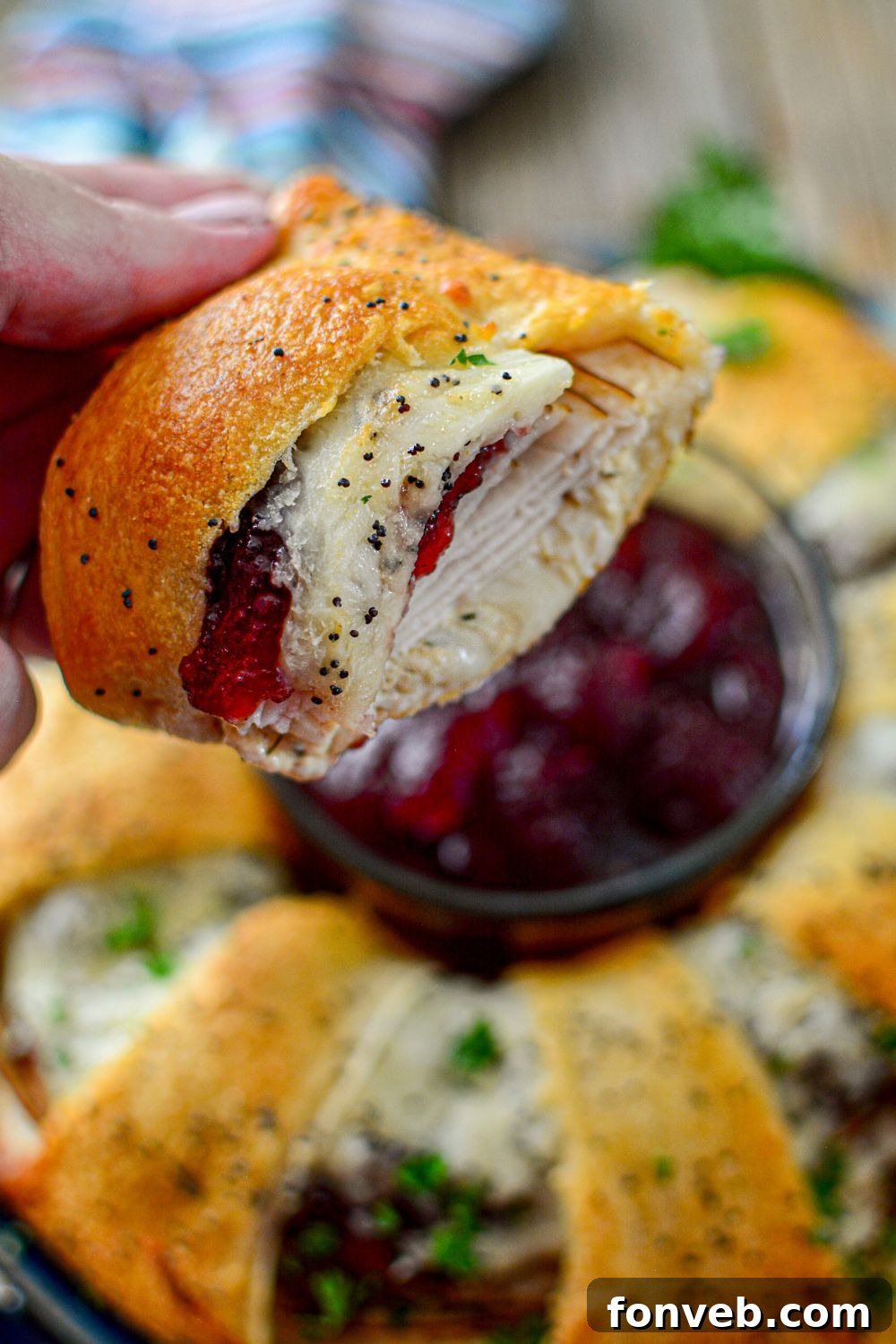 A hand holding a perfectly sliced piece of turkey crescent ring, showing the delicious filling