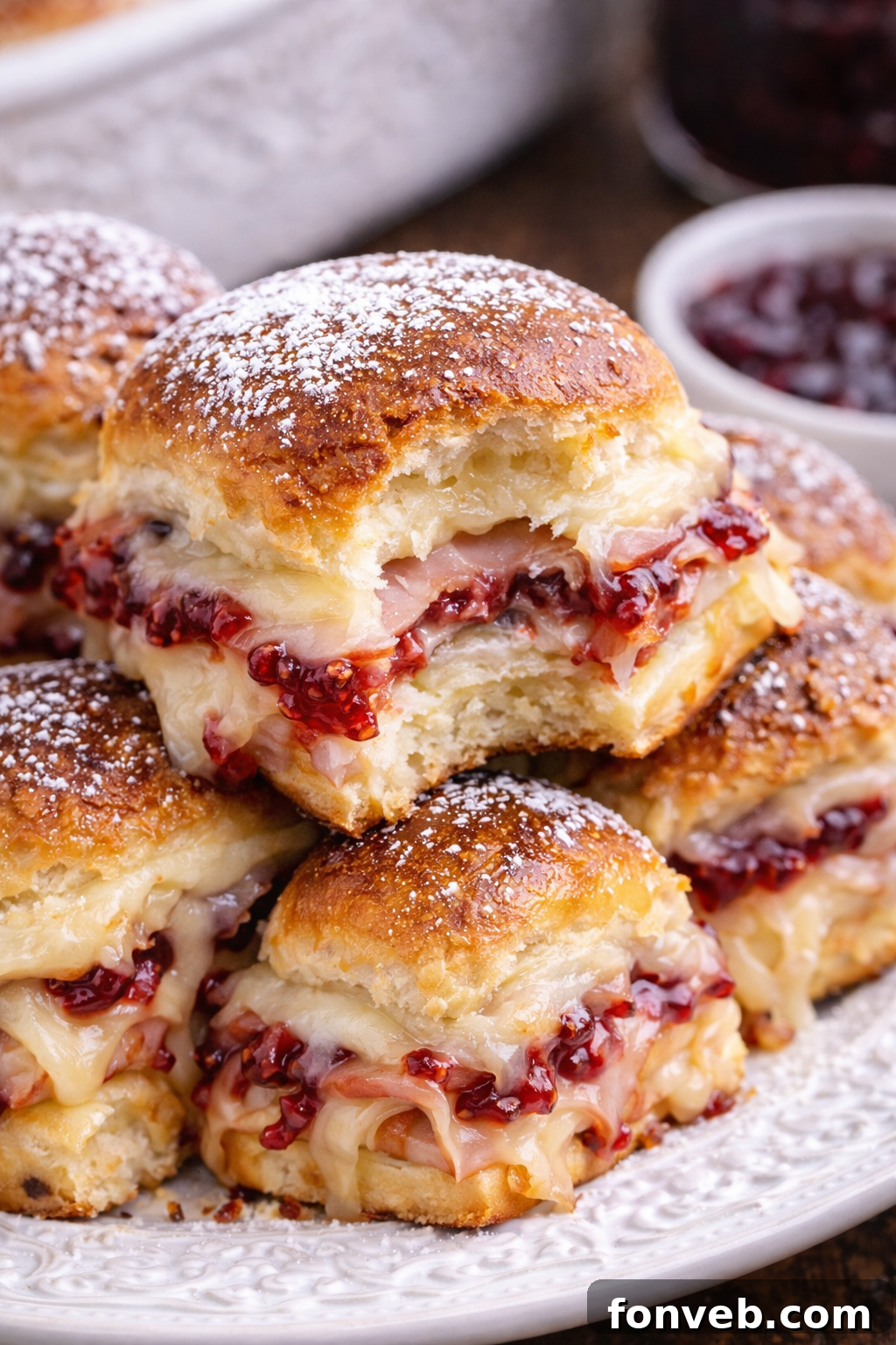 A Monte Cristo Slider on a white plate with a bite taken out, showing the layers of meat and cheese.