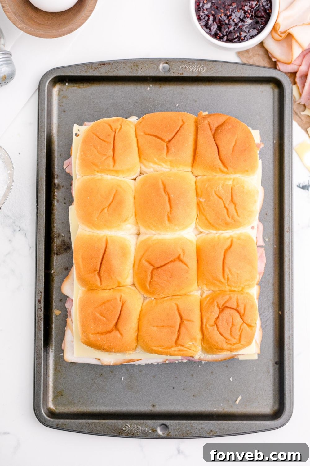 Fully assembled Monte Cristo Sliders ready for the oven on a baking tray.