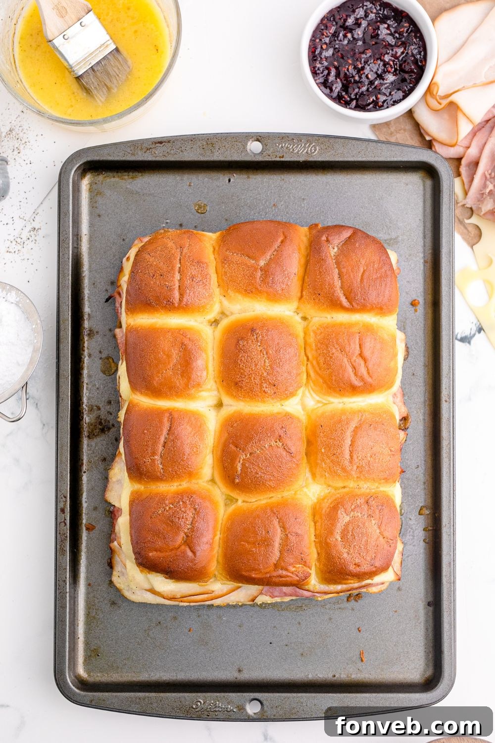 Baked Monte Cristo Sliders with golden-brown tops on a baking tray, fresh from the oven.