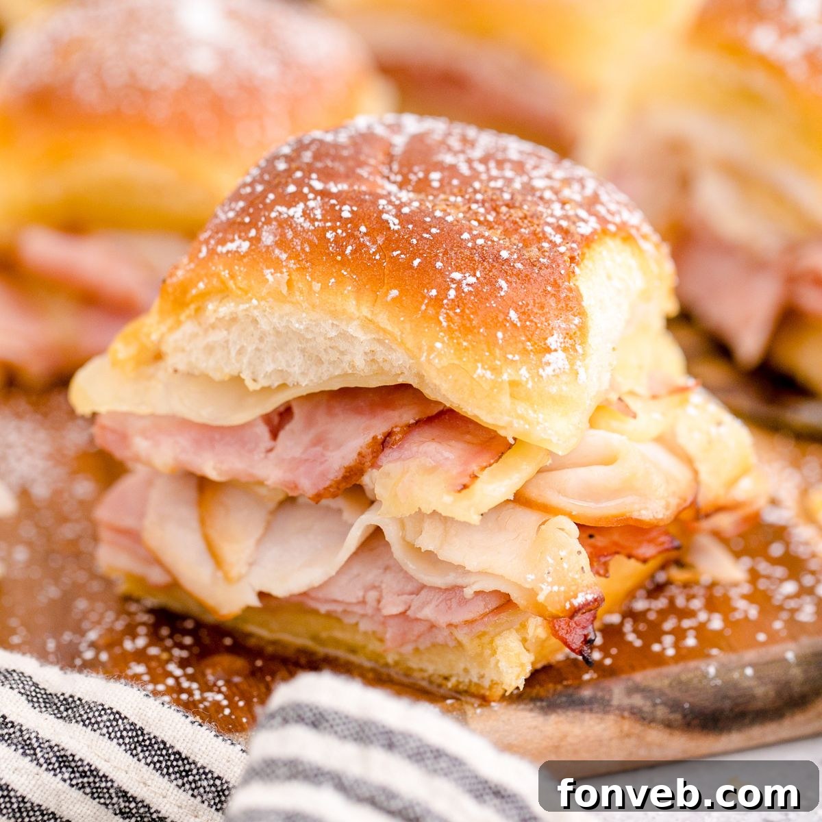 Monte Cristo Sliders arranged neatly on a rustic wooden cutting board.