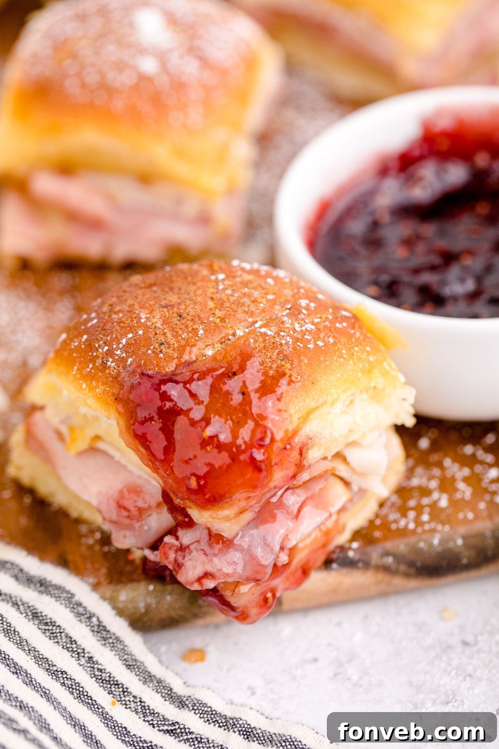 A Monte Cristo slider partially dipped in a bowl of red fruit jam, showing the contrast.