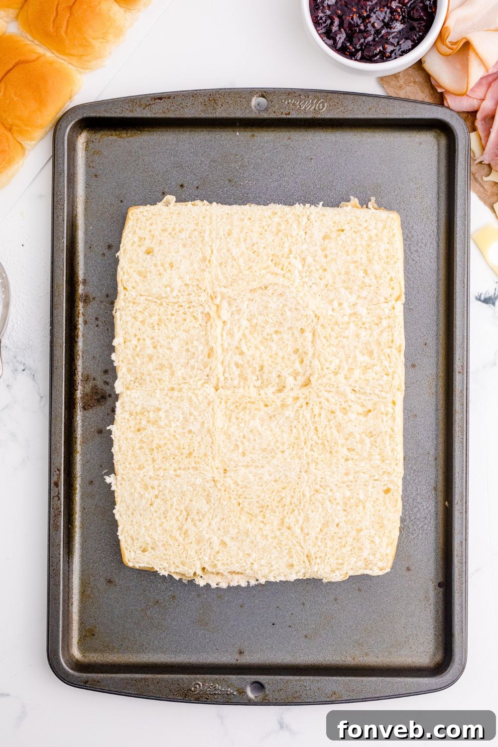 Assembled sliders are sliced and ready to bake on a baking tray.