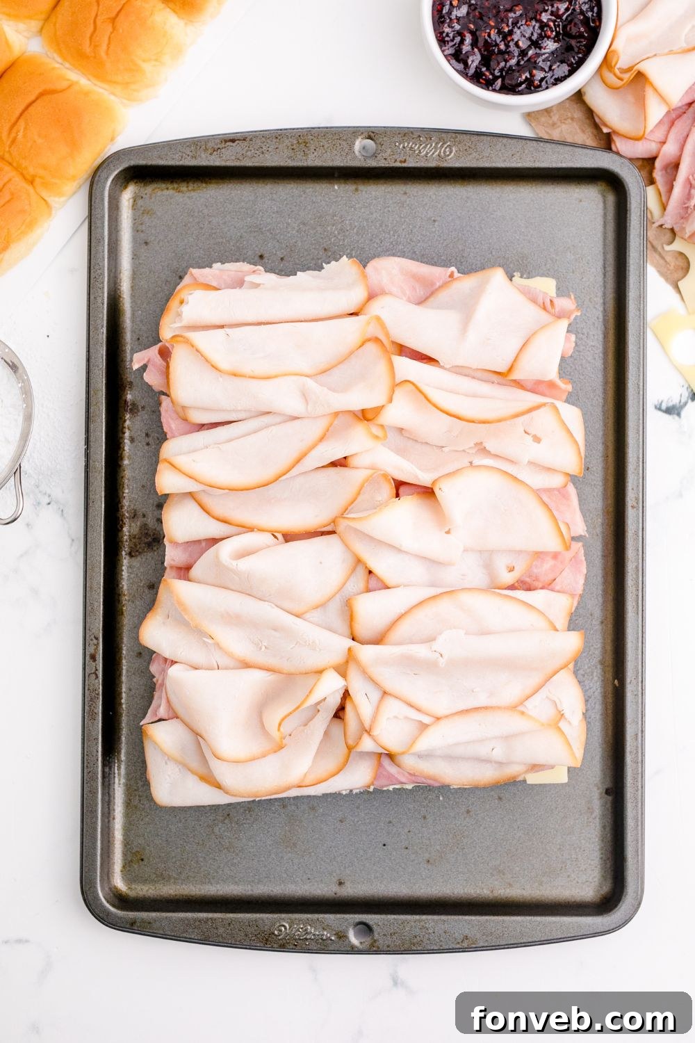 Thinly sliced turkey lunch meat layered over ham on slider buns.