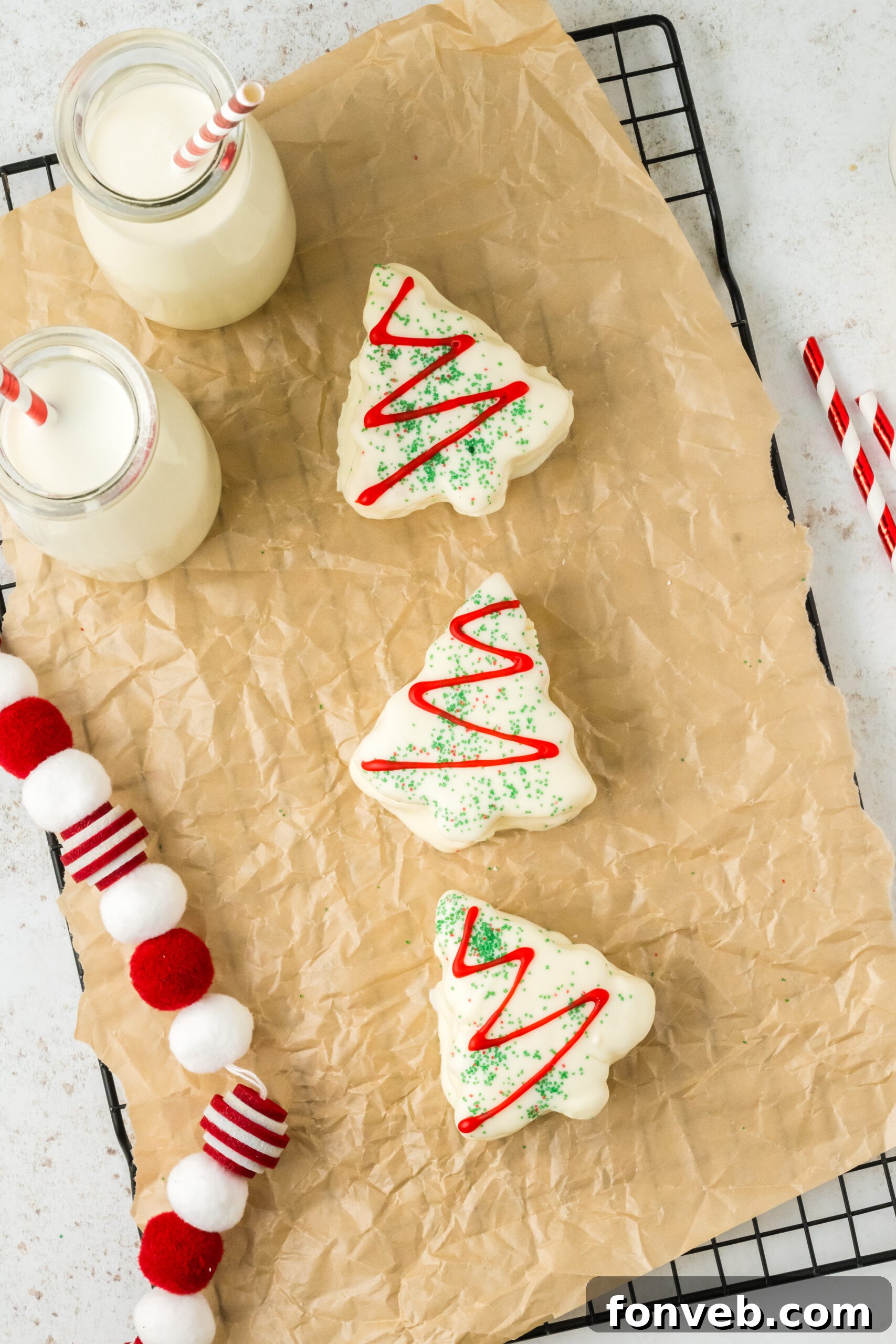 Christmas Tree Snack Cakes from Scratch 14 Little Debbie Christmas Tree Cakes on a parchment paper tray with glasses of milk around it