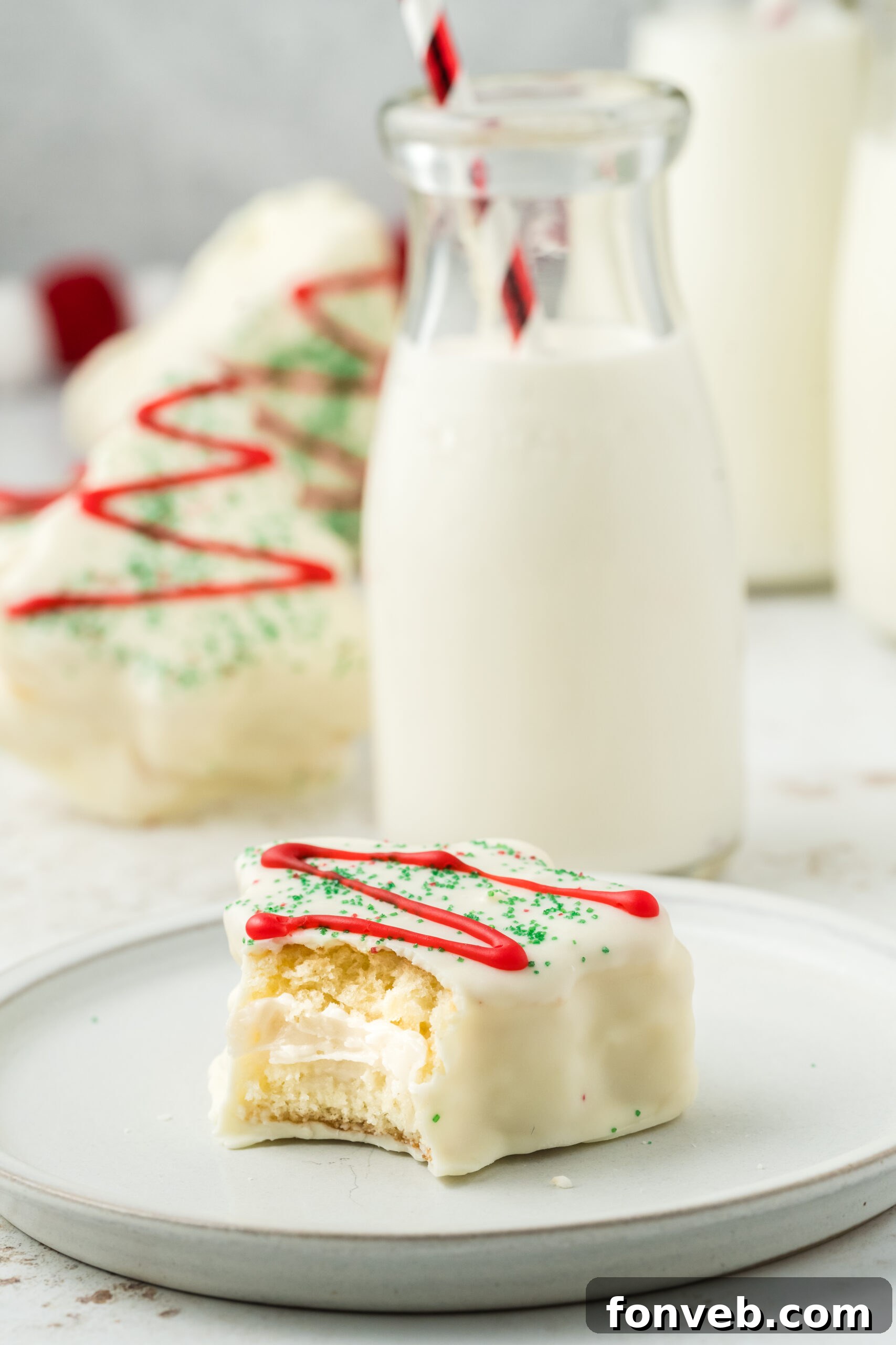 Christmas Tree Snack Cakes from Scratch 21 A bite taken out of a mini Christmas tree cake on a plate with a glass of milk beside it
