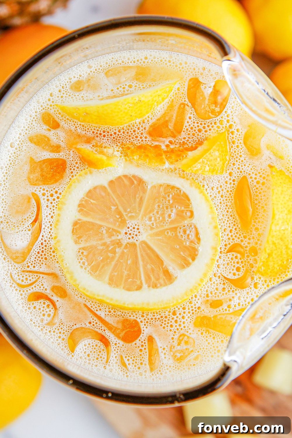 overhead look of party punch in a glass pitcher on table garnishes with sliced fruit