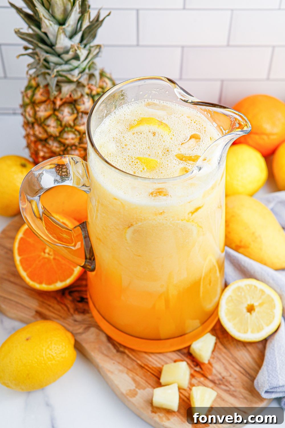party punch in a glass pitcher sitting on table with fruit all around it