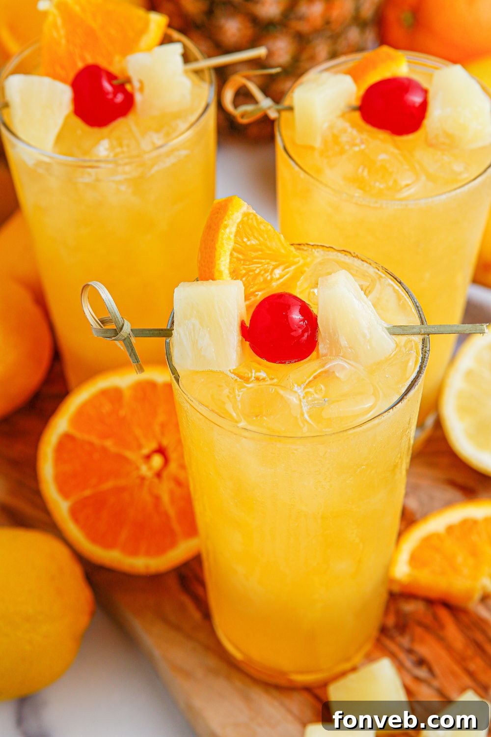Tropical Lemonade Punch in glasses on table with fruit around it on table 