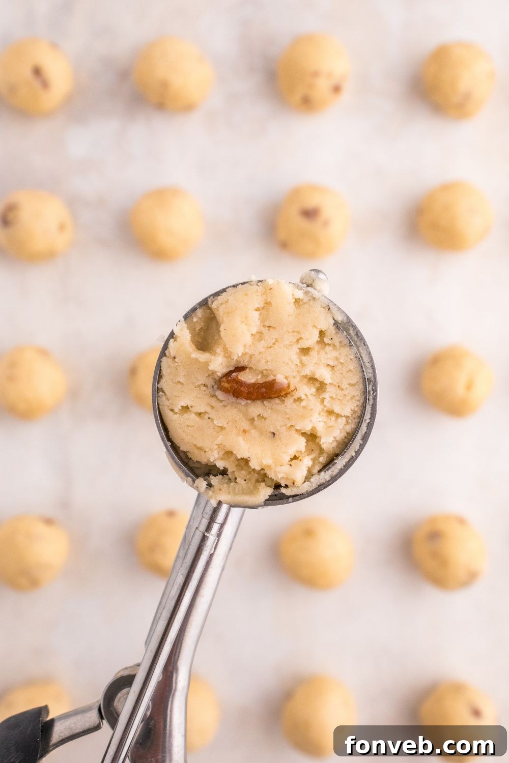 cookie scoop with snowball cookie batter in it 