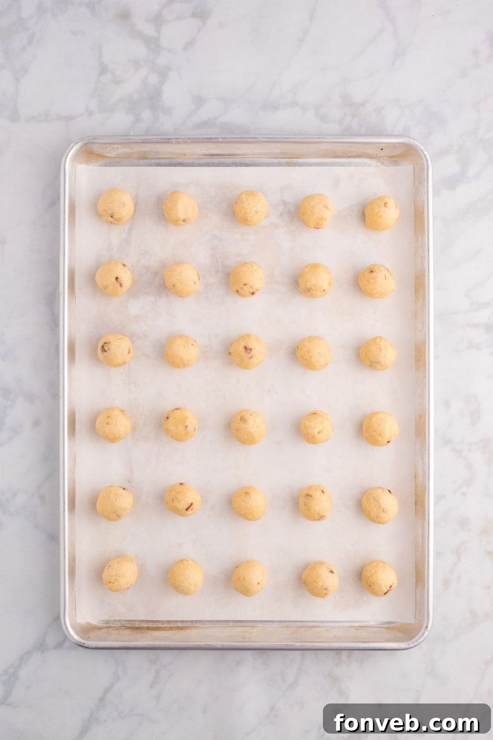 raw cookie balls on a baking sheet on table 