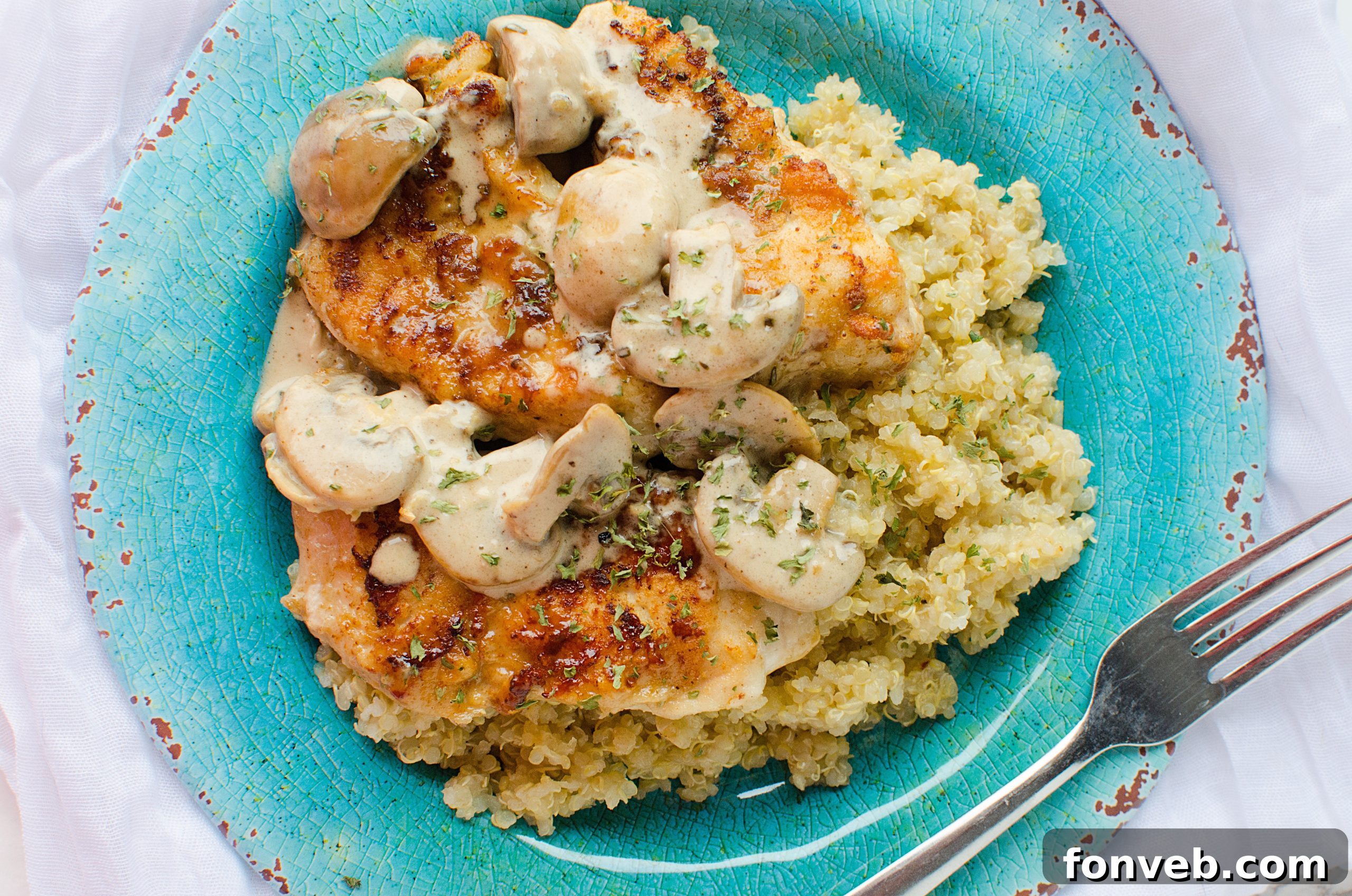 Creamy Asiago chicken served over a bed of pasta, garnished with fresh herbs