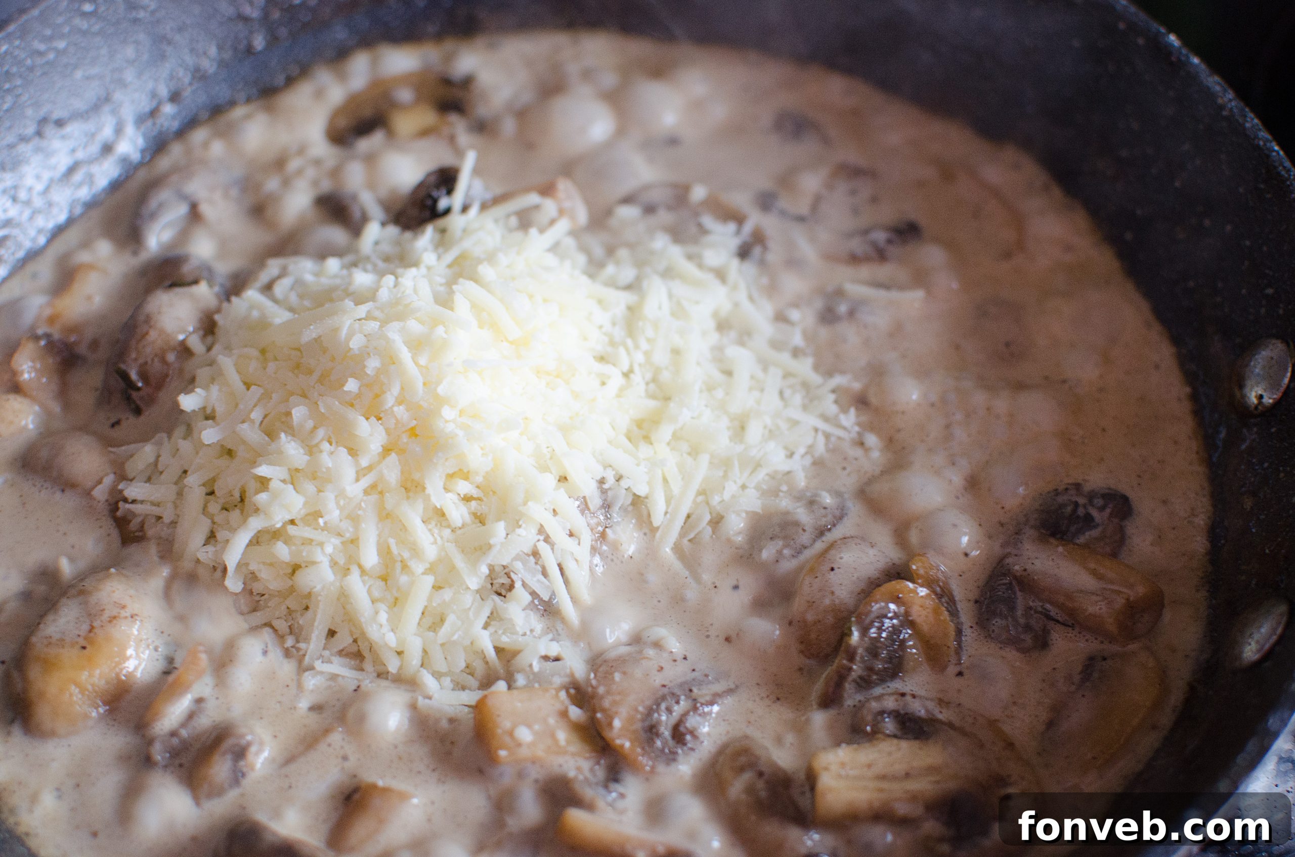 Close-up of golden brown chicken pieces and sautéed mushrooms in a skillet