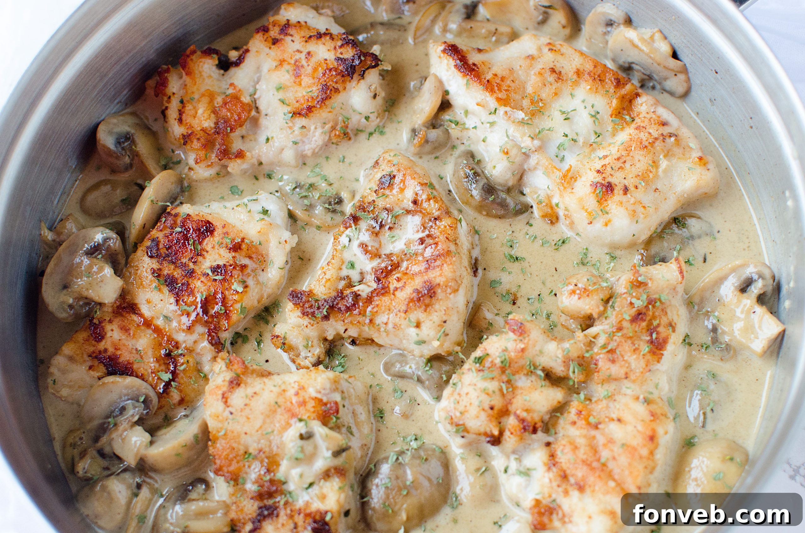 Creamy Asiago chicken simmering in a rich white wine sauce with mushrooms