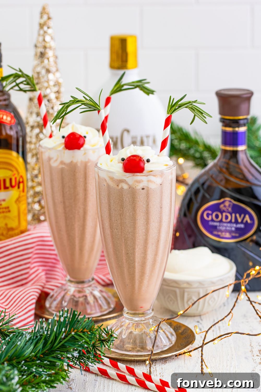 Drunken Rudolph drinks in tall glasses, surrounded by ingredients and festive decorations on a holiday-themed table.