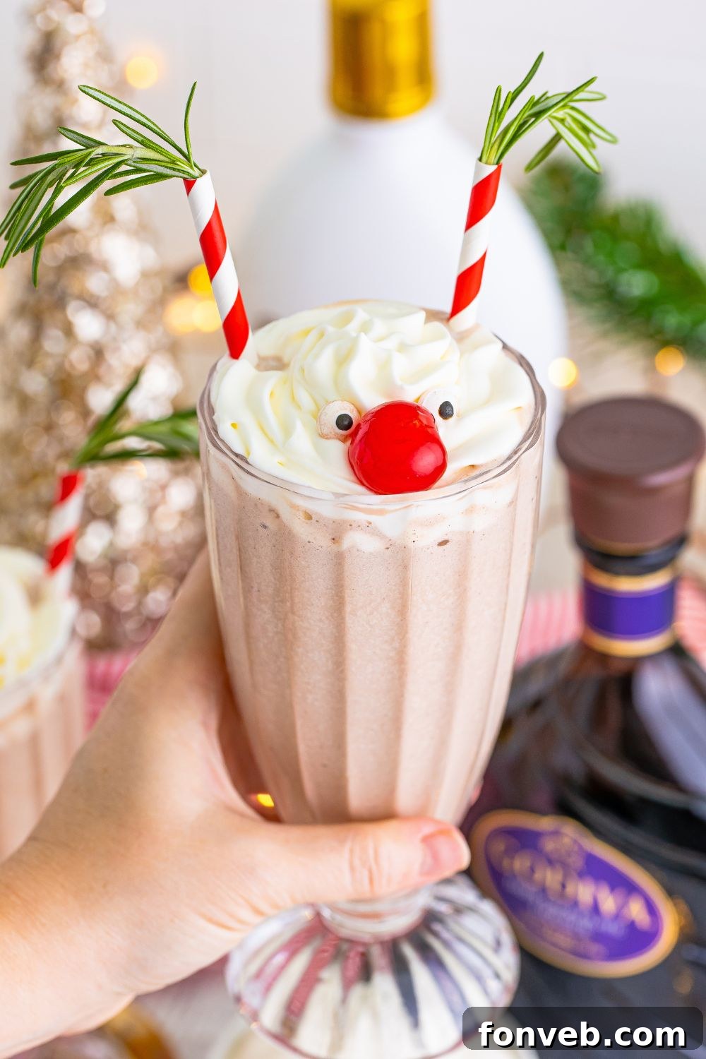 A Drunk Rudolph Cocktail held firmly in a hand, highlighting its whimsical decorations and festive charm.